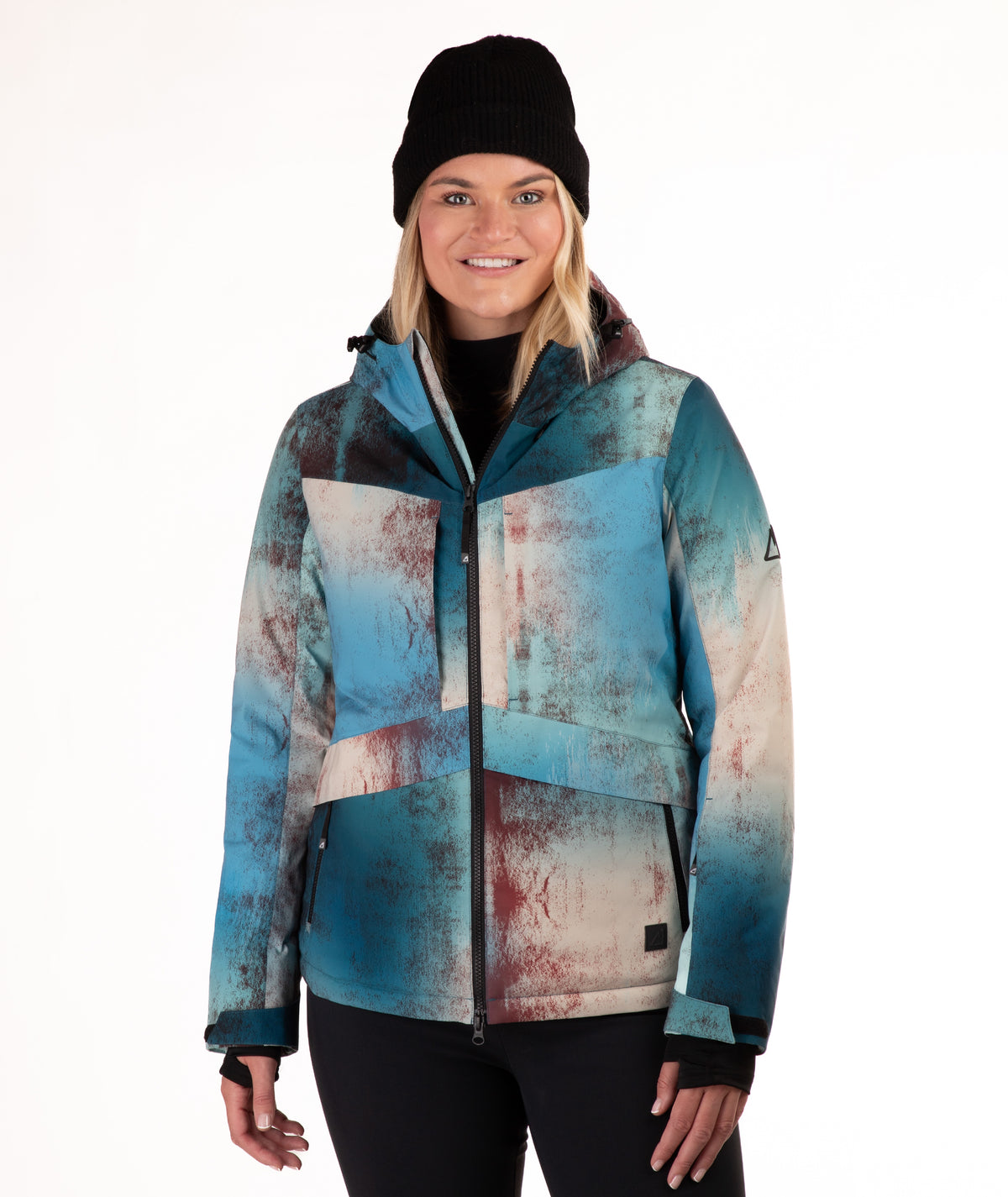 A woman wearing a blue and beige abstract-patterned ski jacket, a black beanie, and black pants, standing against a plain white background.