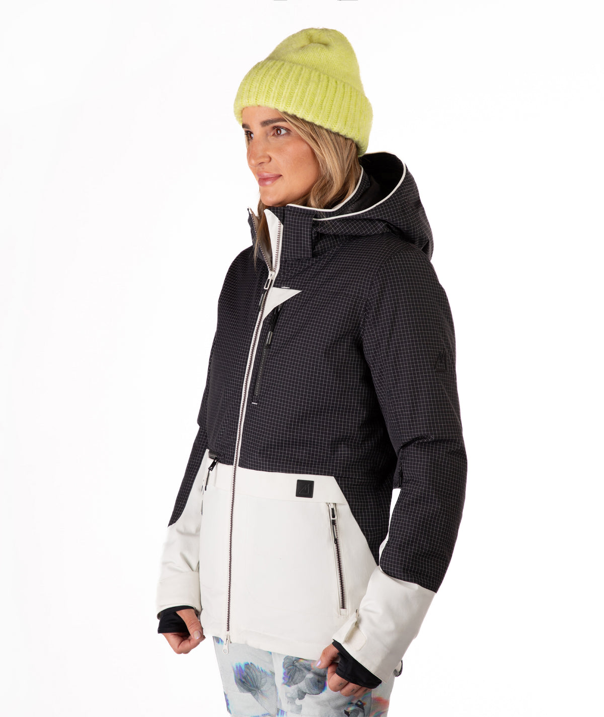 Person wearing a black and white jacket with a yellow beanie on a white background