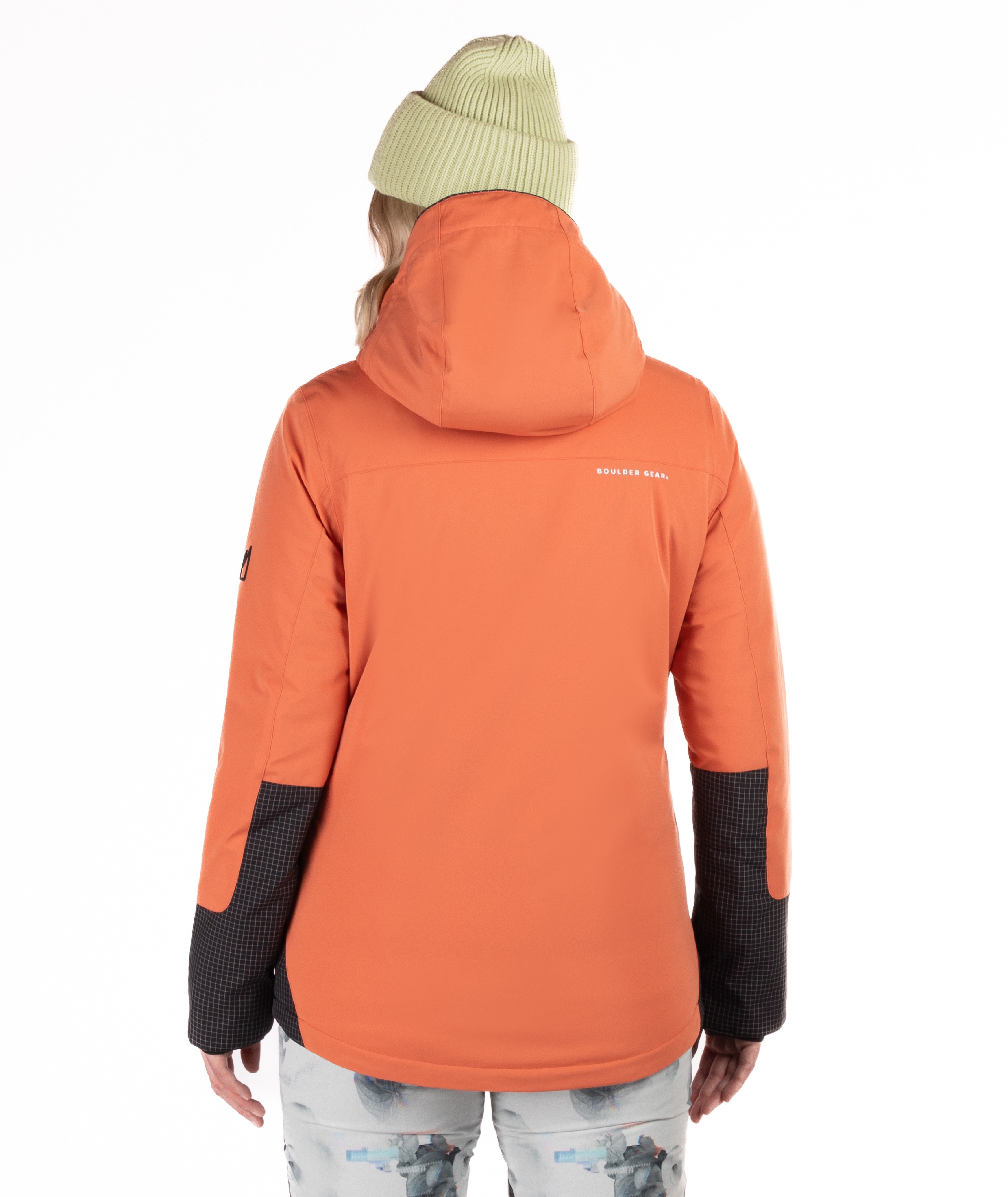 Person wearing an orange jacket with checkered back arm detail and a brand logo on the back, standing against a white background.