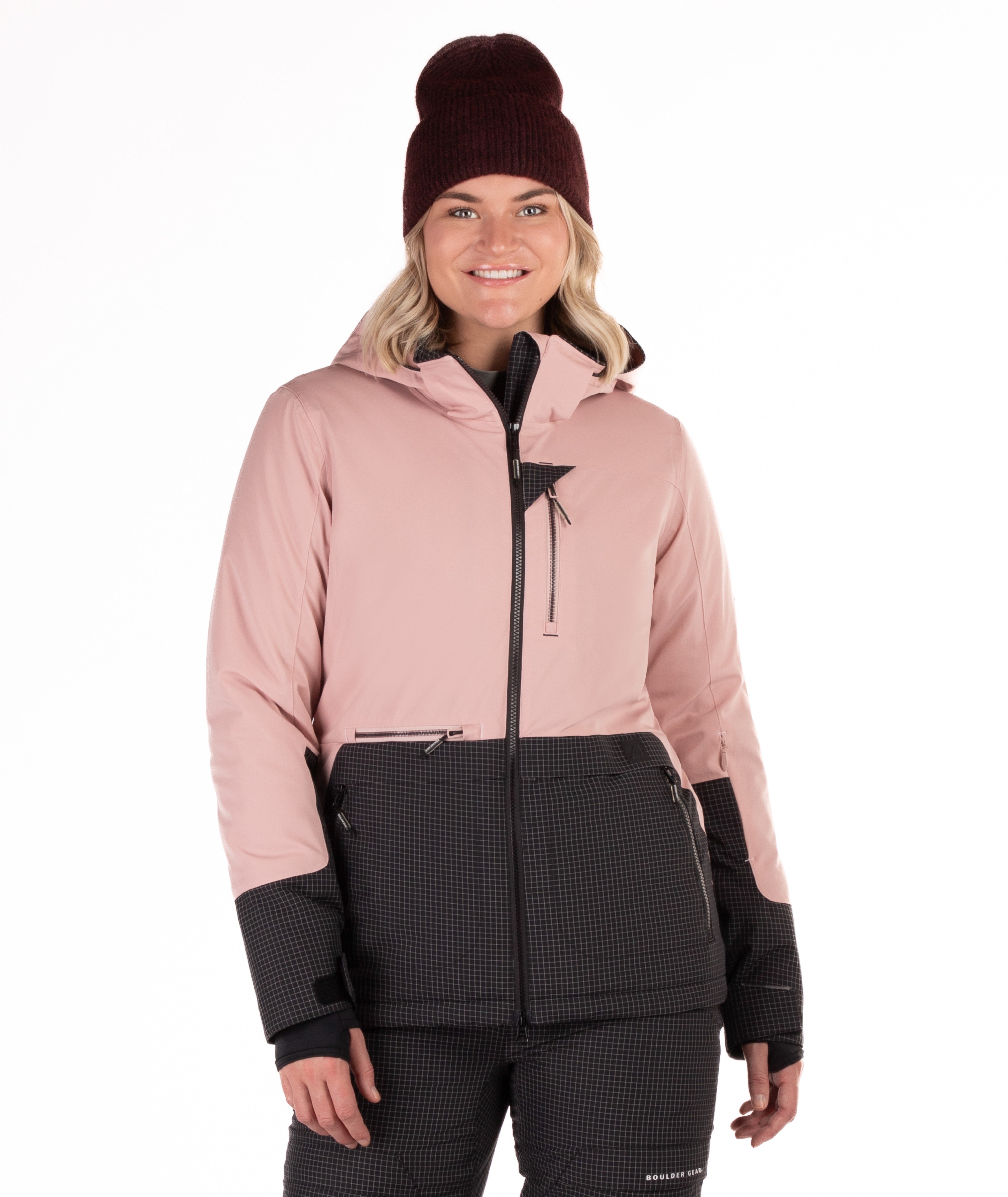 Woman wearing a two-tone pink and black check snow jacket with a white background