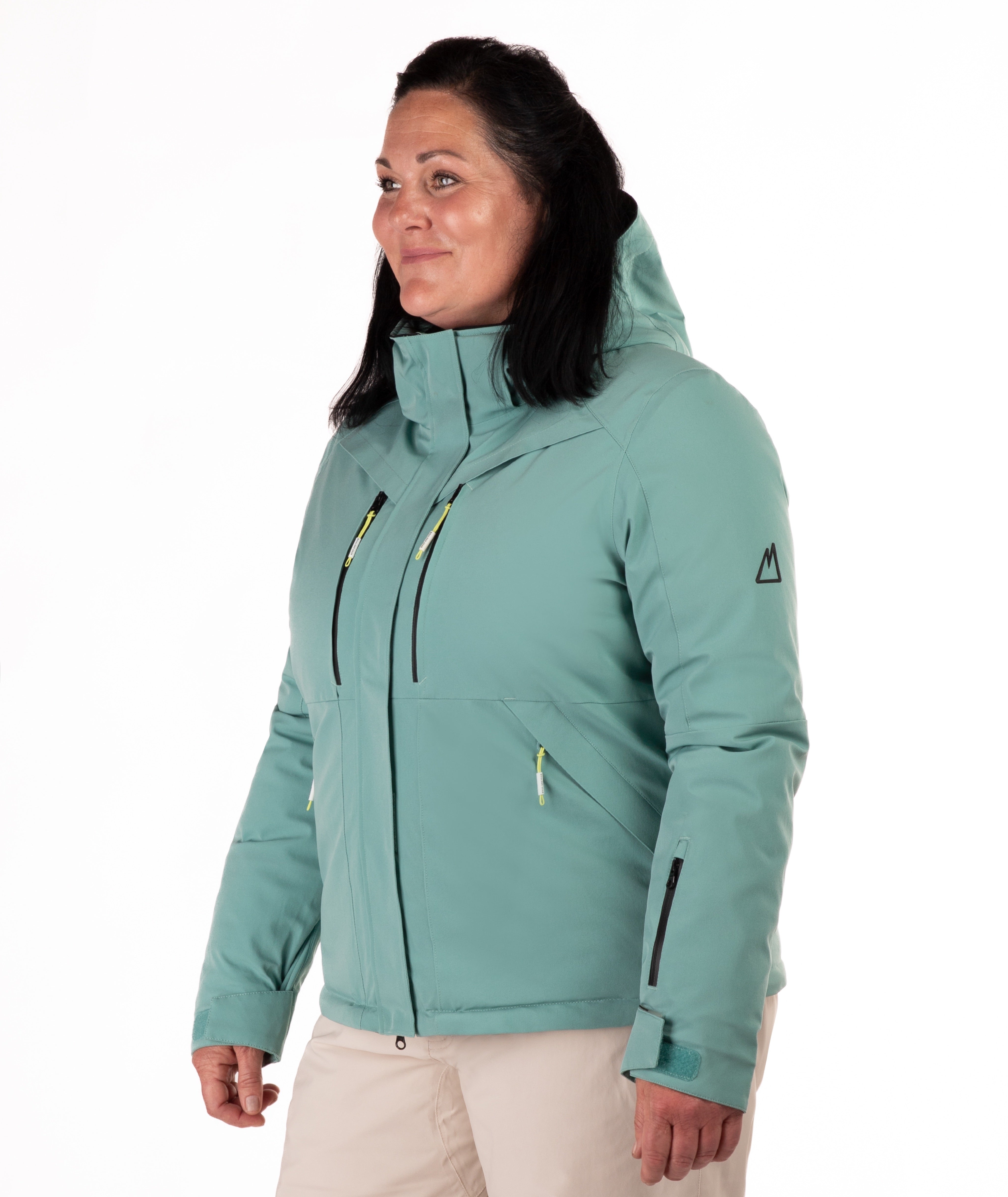 Woman wearing a teal snow jacket with black chest zippers on a white background