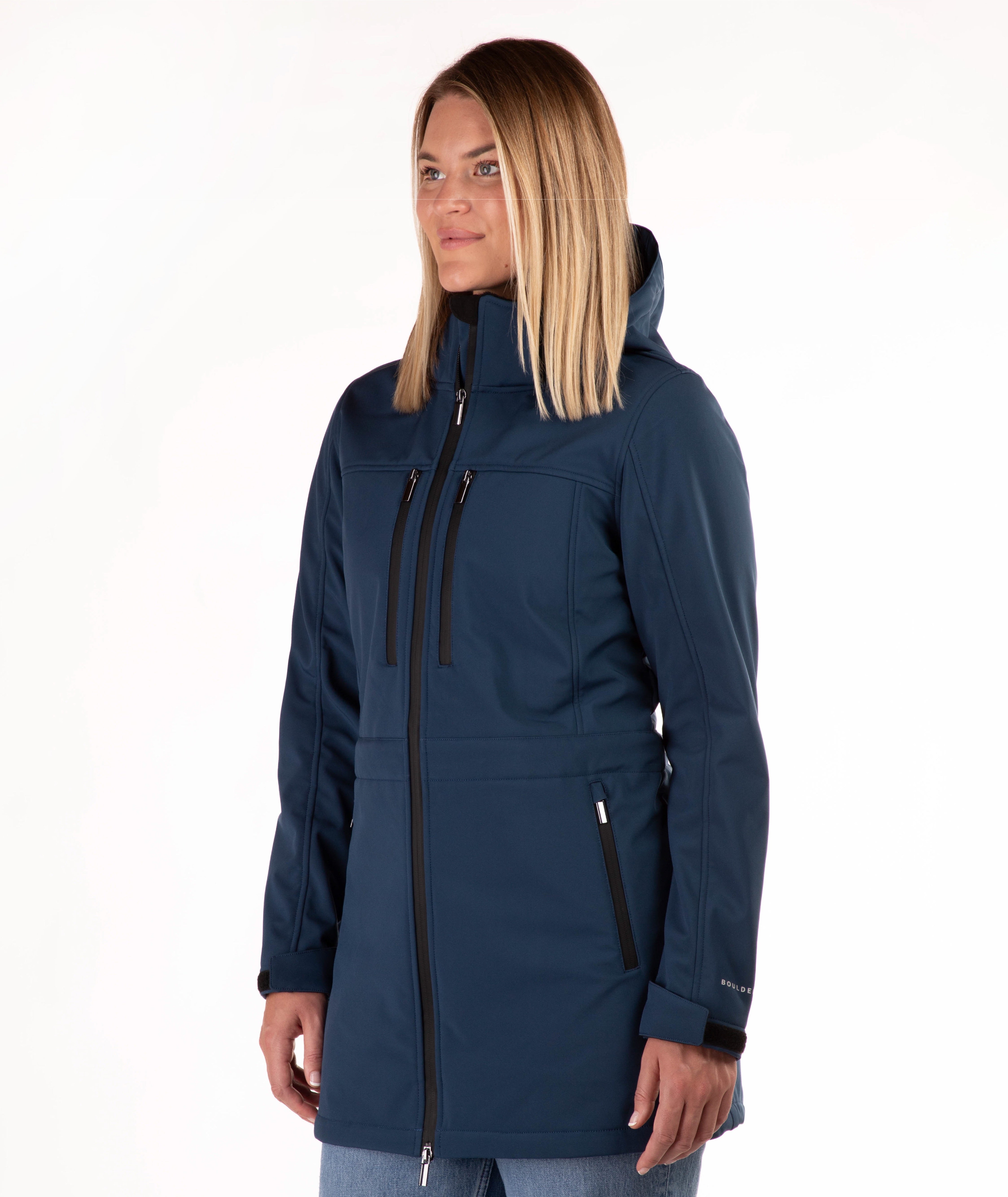 A woman modeling a navy blue hooded softshell jacket with black zippers and trim, shown from the waist up against a plain white studio background.
