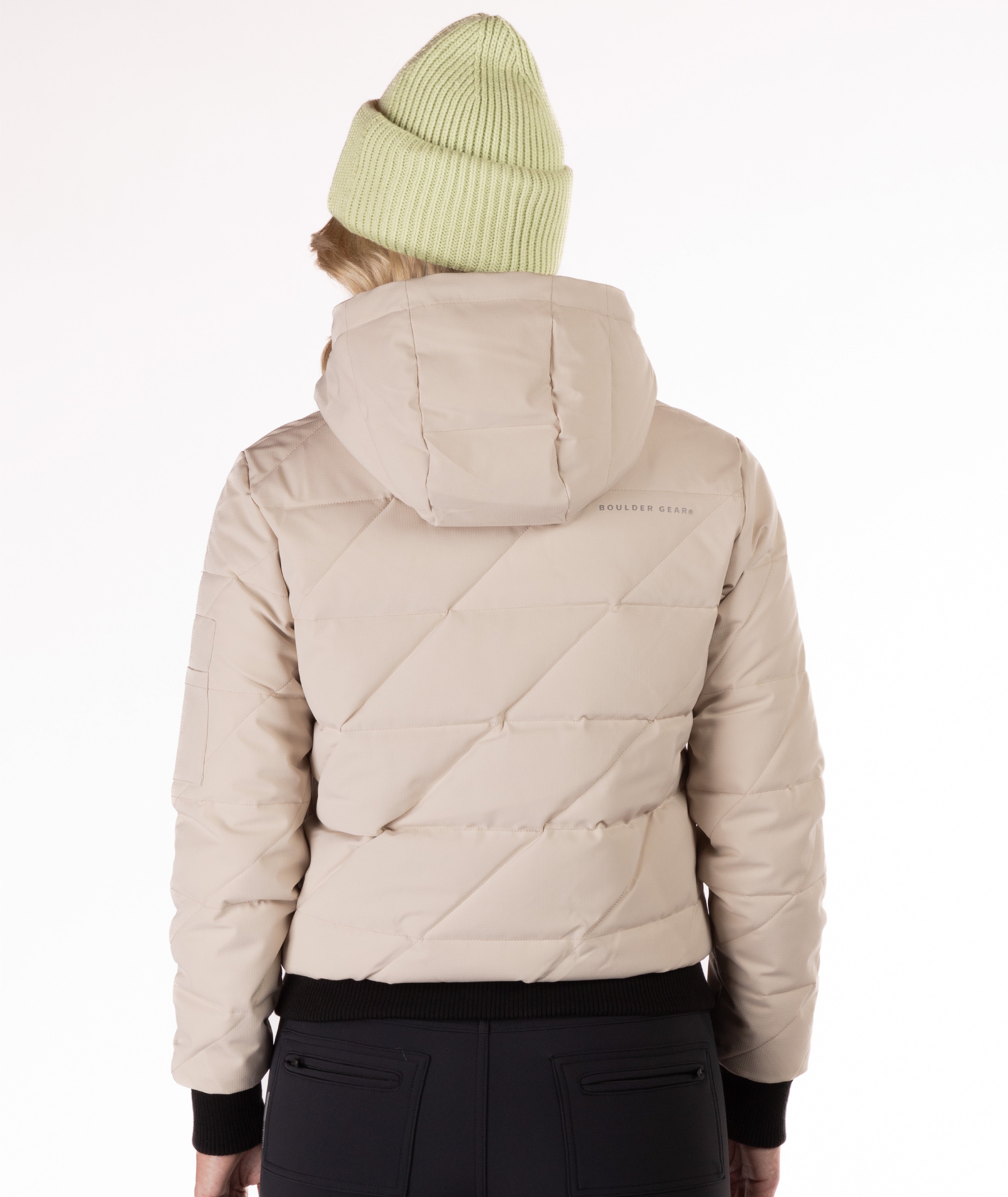 Beige quilted jacket with a hood worn by a person on a white background, back view of the jacket highlighting a Boulder Gear brand logo.