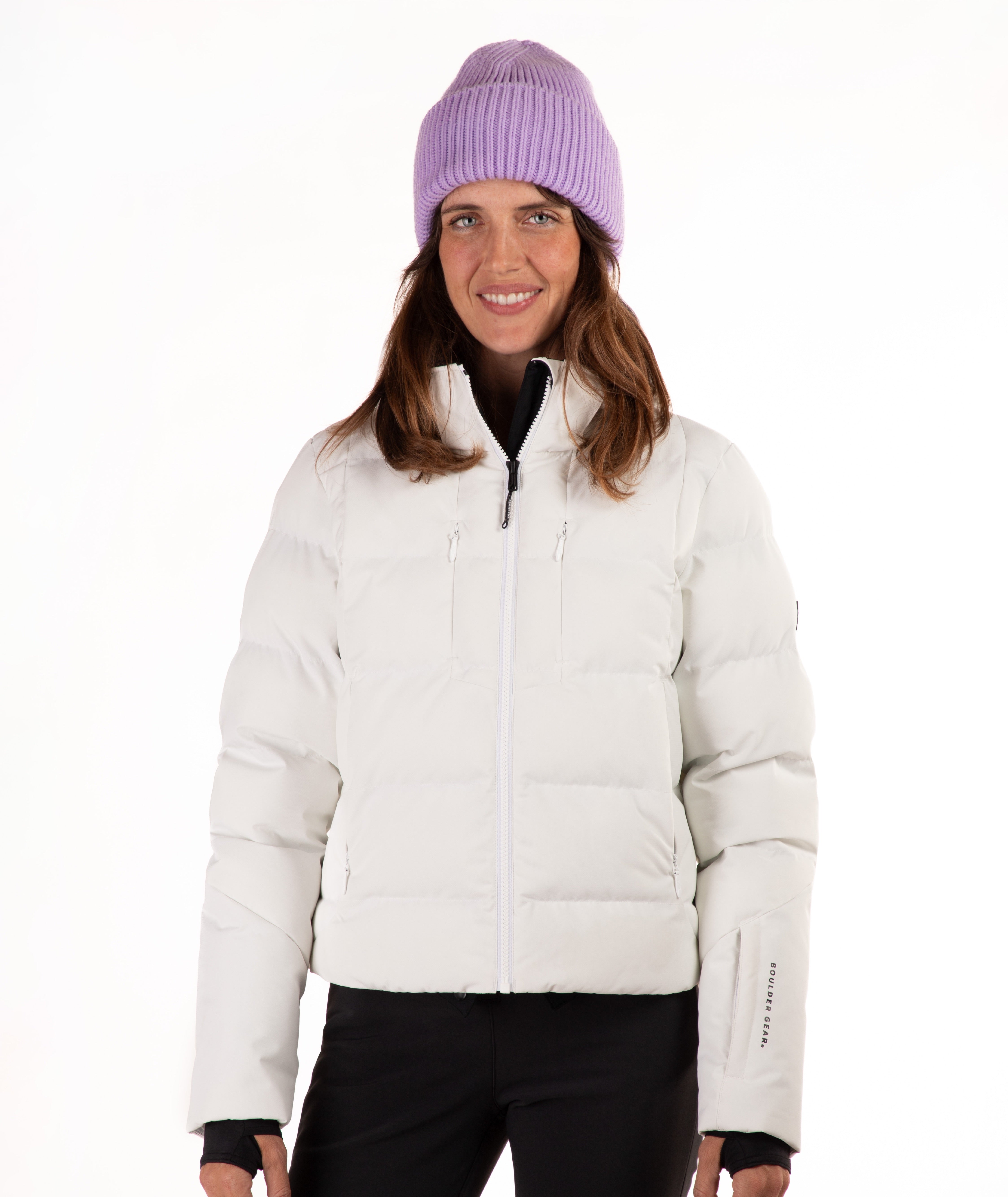 A woman wearing a off white puffer jacket, black pants, and a light purple knit beanie, standing against a plain white background.
