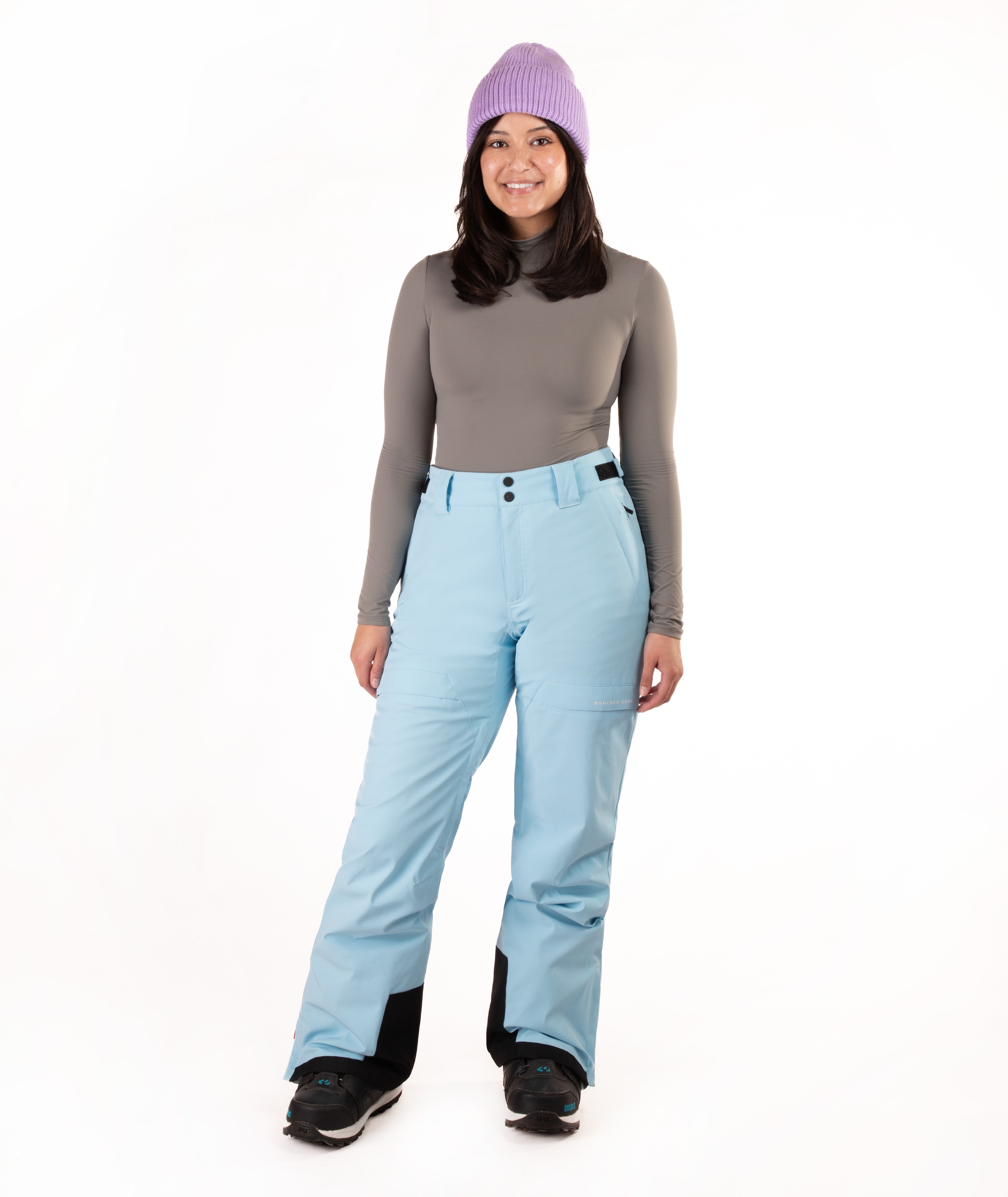 Person wearing light blue snow pants and a gray top with a white background