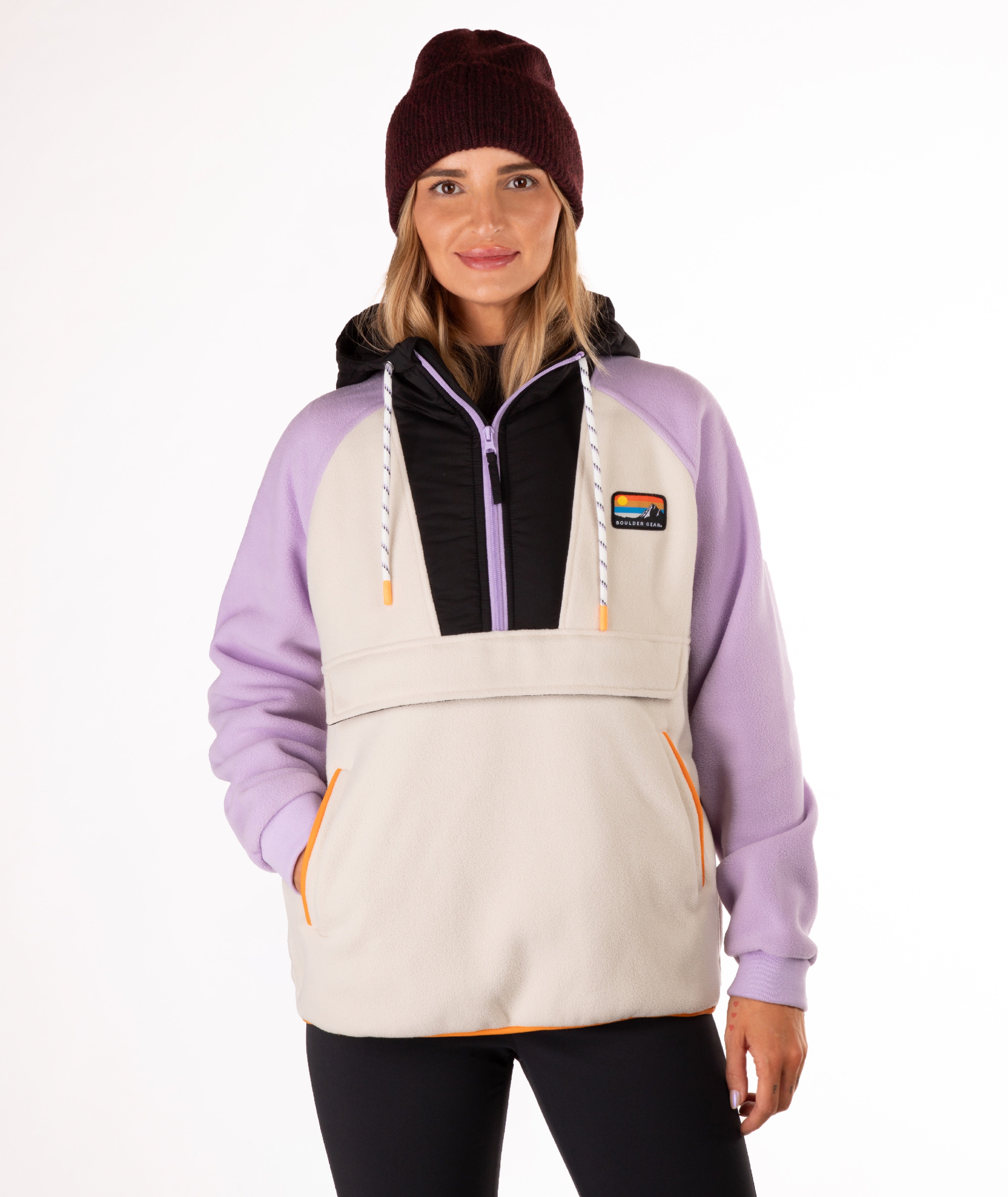 Woman wearing a light purple and beige fleece pullover with a visible brand logo and orange detailing on a white background