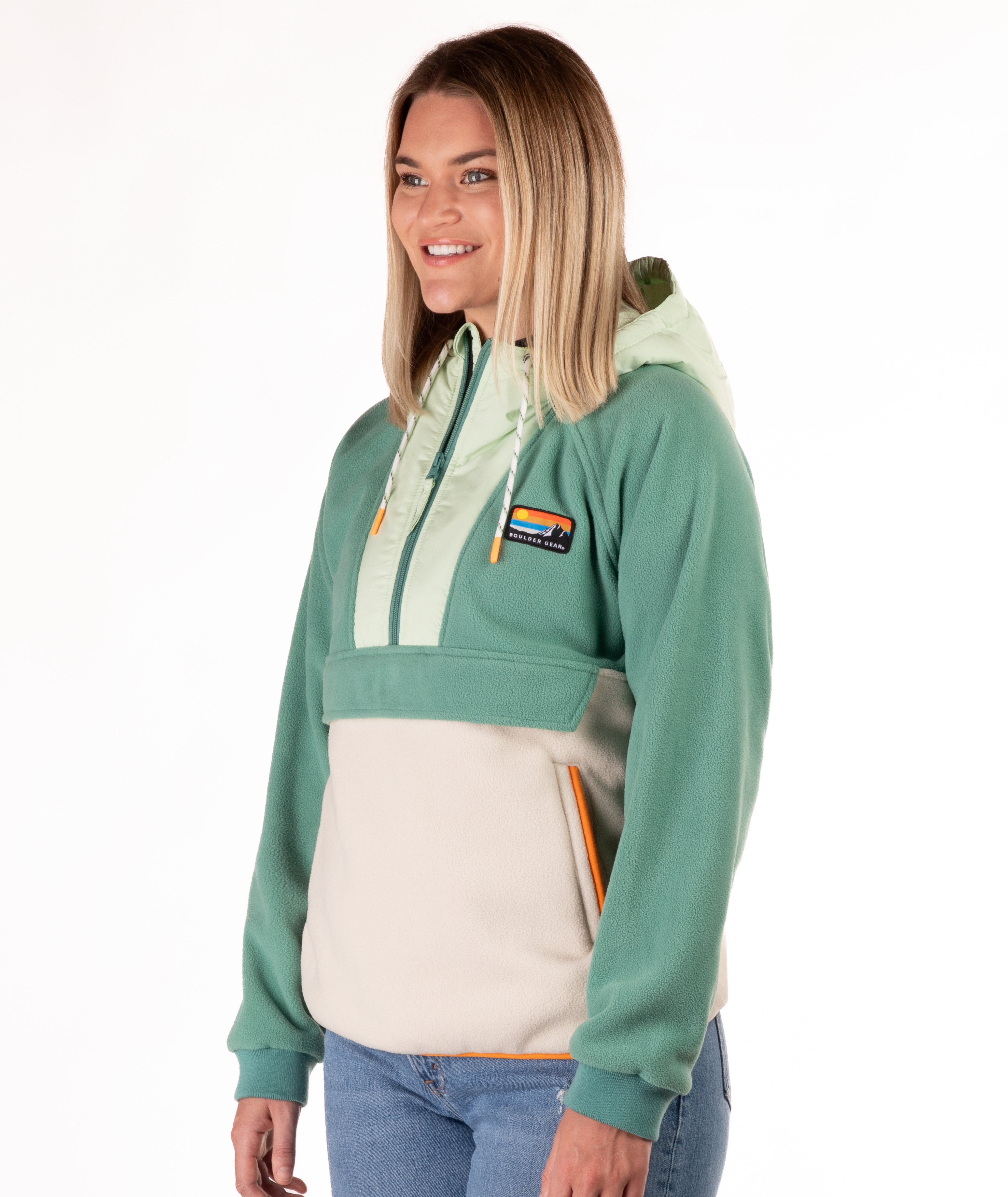 Woman wearing a green and beige fleece pullover with a visible brand logo and orange detailing on a white background