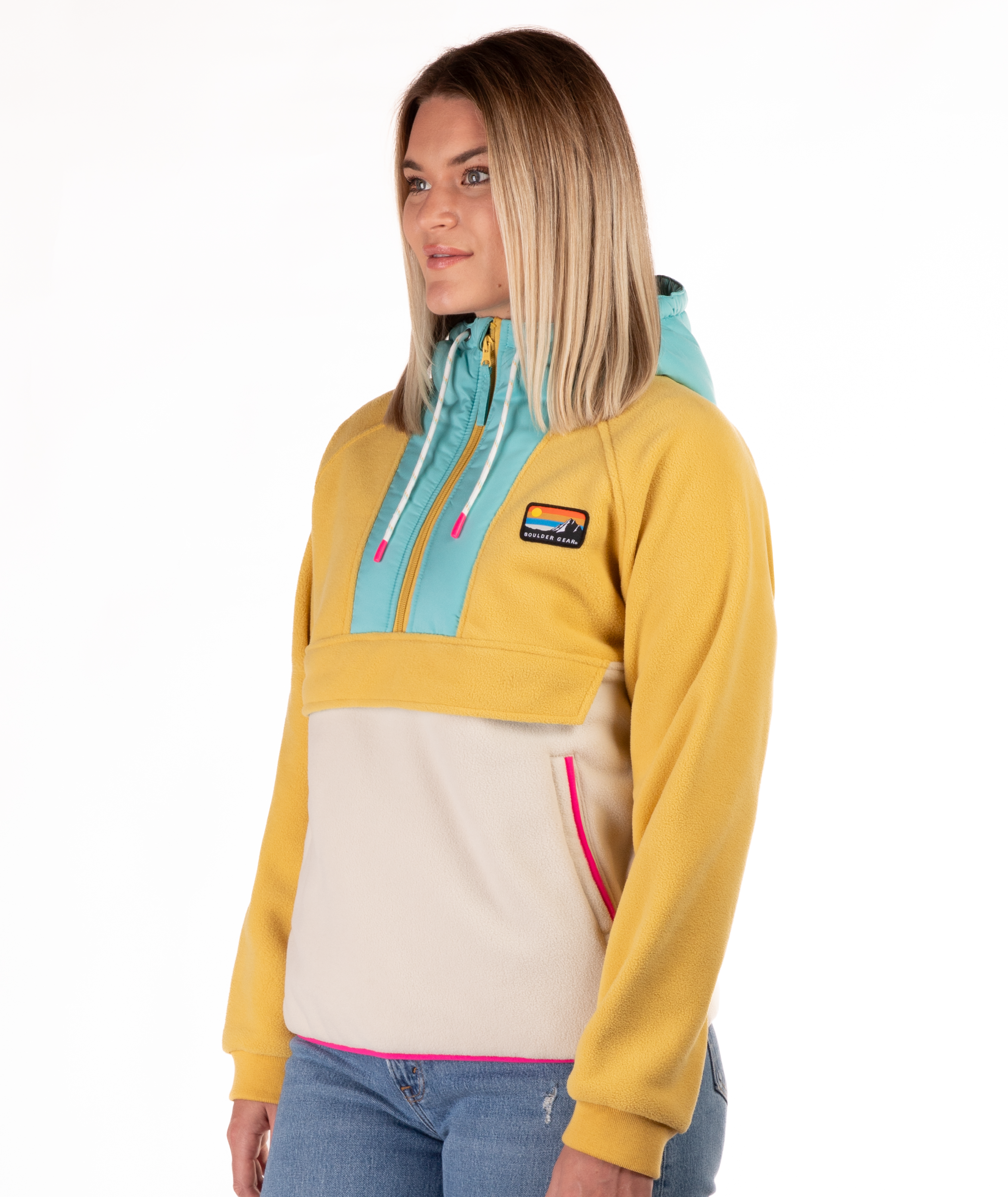Woman wearing a yellow, blue and beige fleece pullover with a visible brand logo and pink detailing on a white background