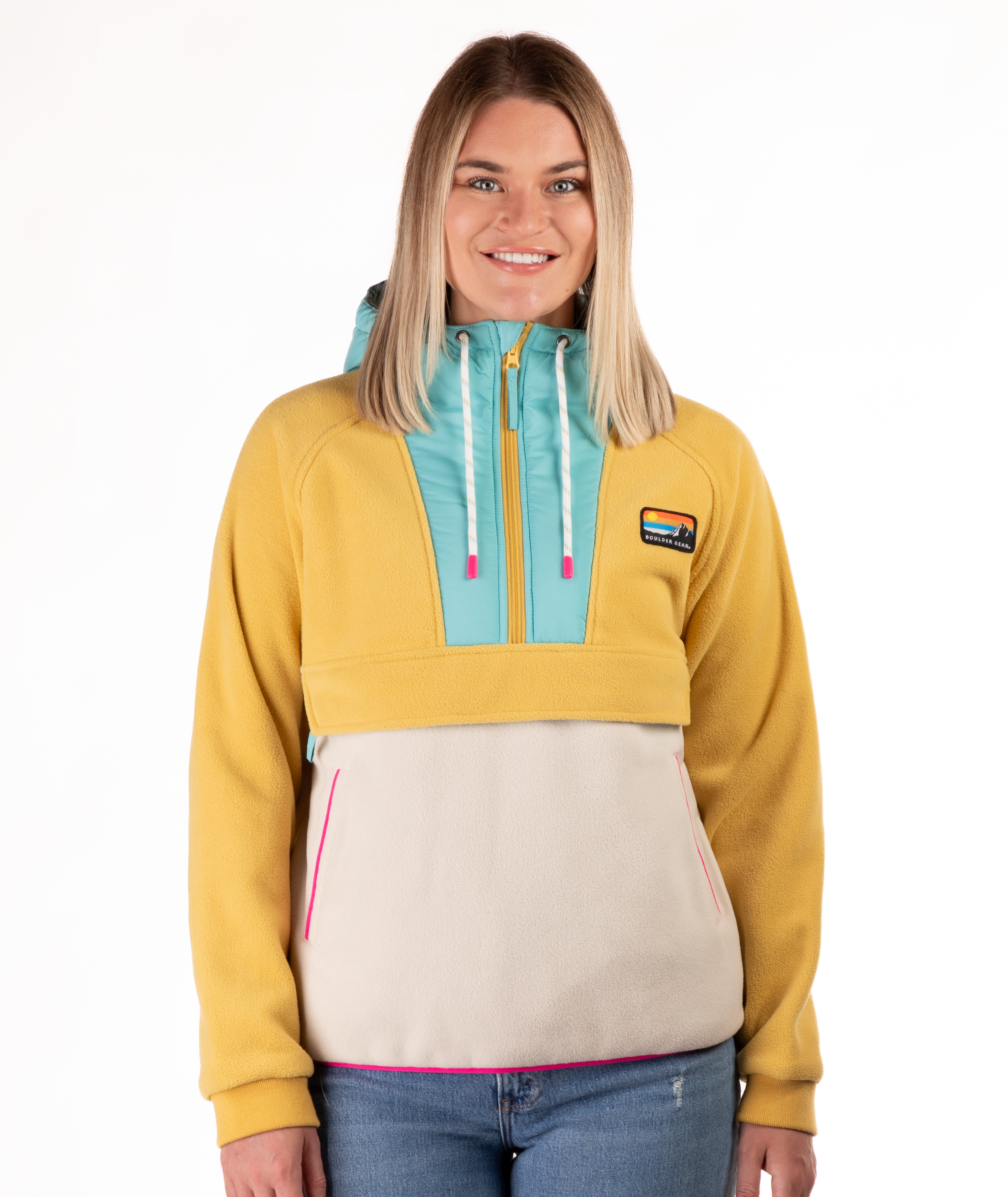 Woman wearing a yellow, blue and beige fleece pullover with a visible brand logo and pink detailing on a white background