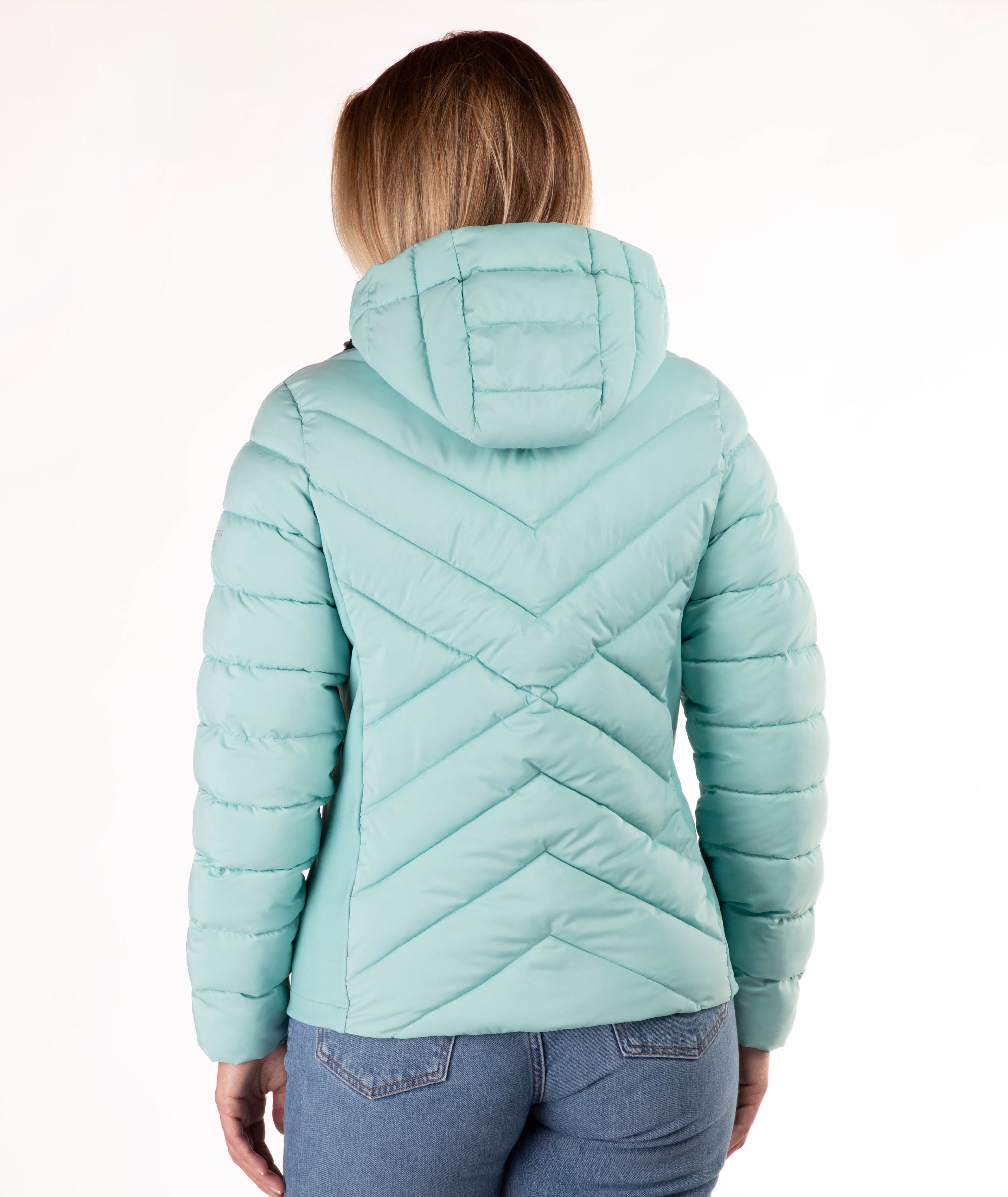 A woman viewed from behind wearing a light mint green hooded puffer jacket with a chevron quilted pattern on the back, paired with blue jeans, against a plain white background.