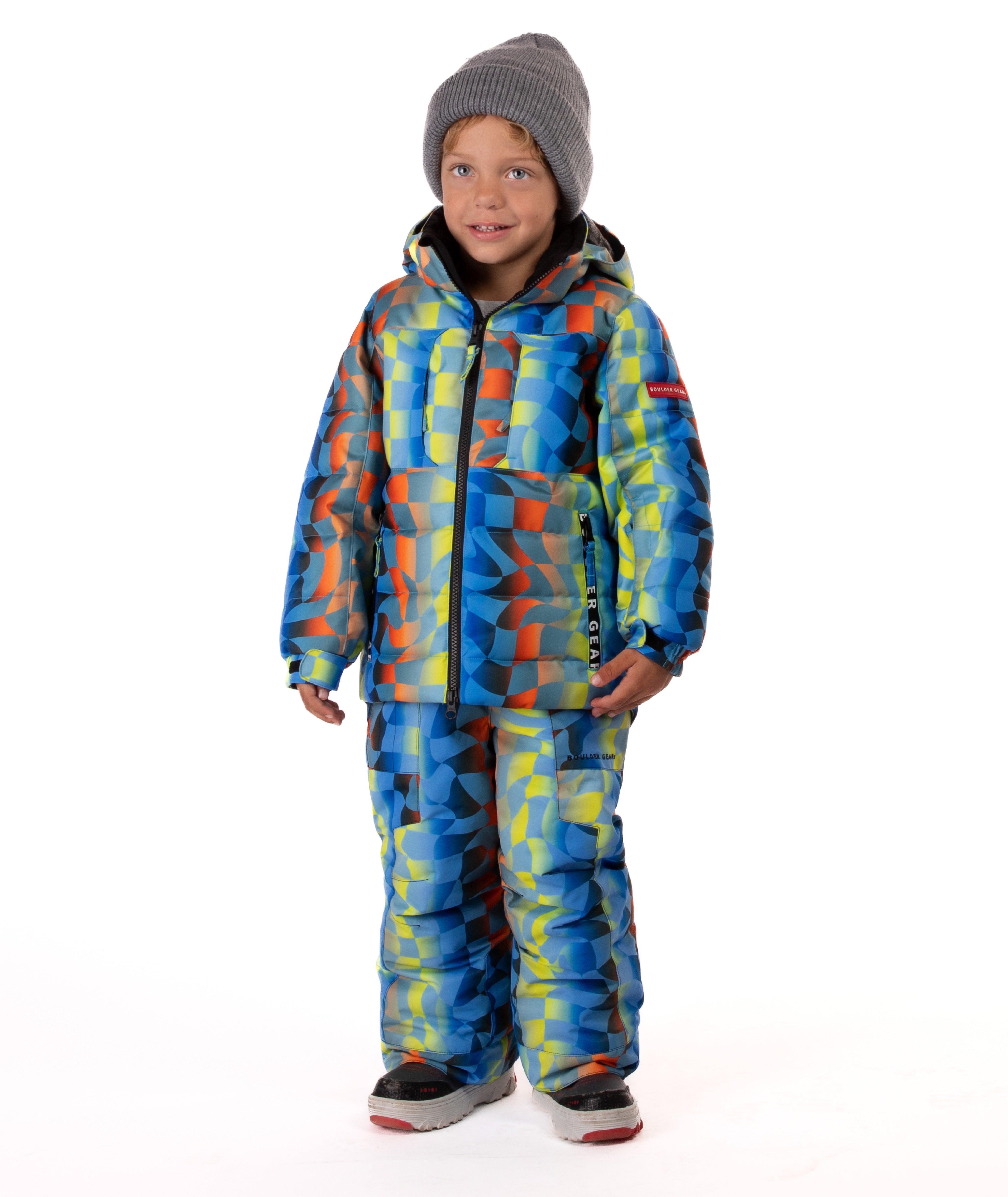 Child wearing a yellow, blue, and orange multi color geometric print quilted winter jacket with chest pockets and hand-warmer pockets on a white background