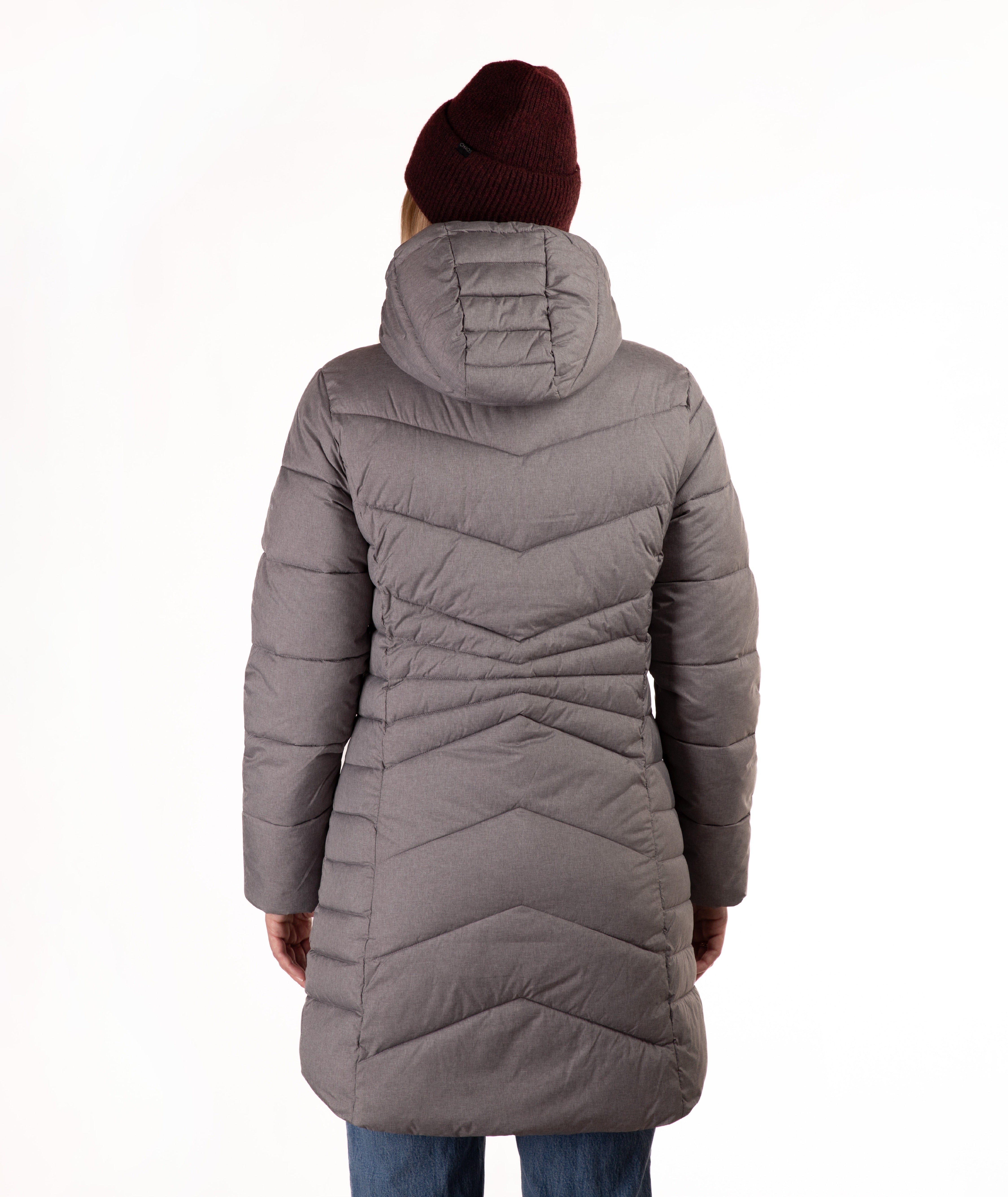 A person shown from the back wearing a long gray hooded puffer coat, a dark burgundy knit beanie, and blue jeans against a plain white studio background.
