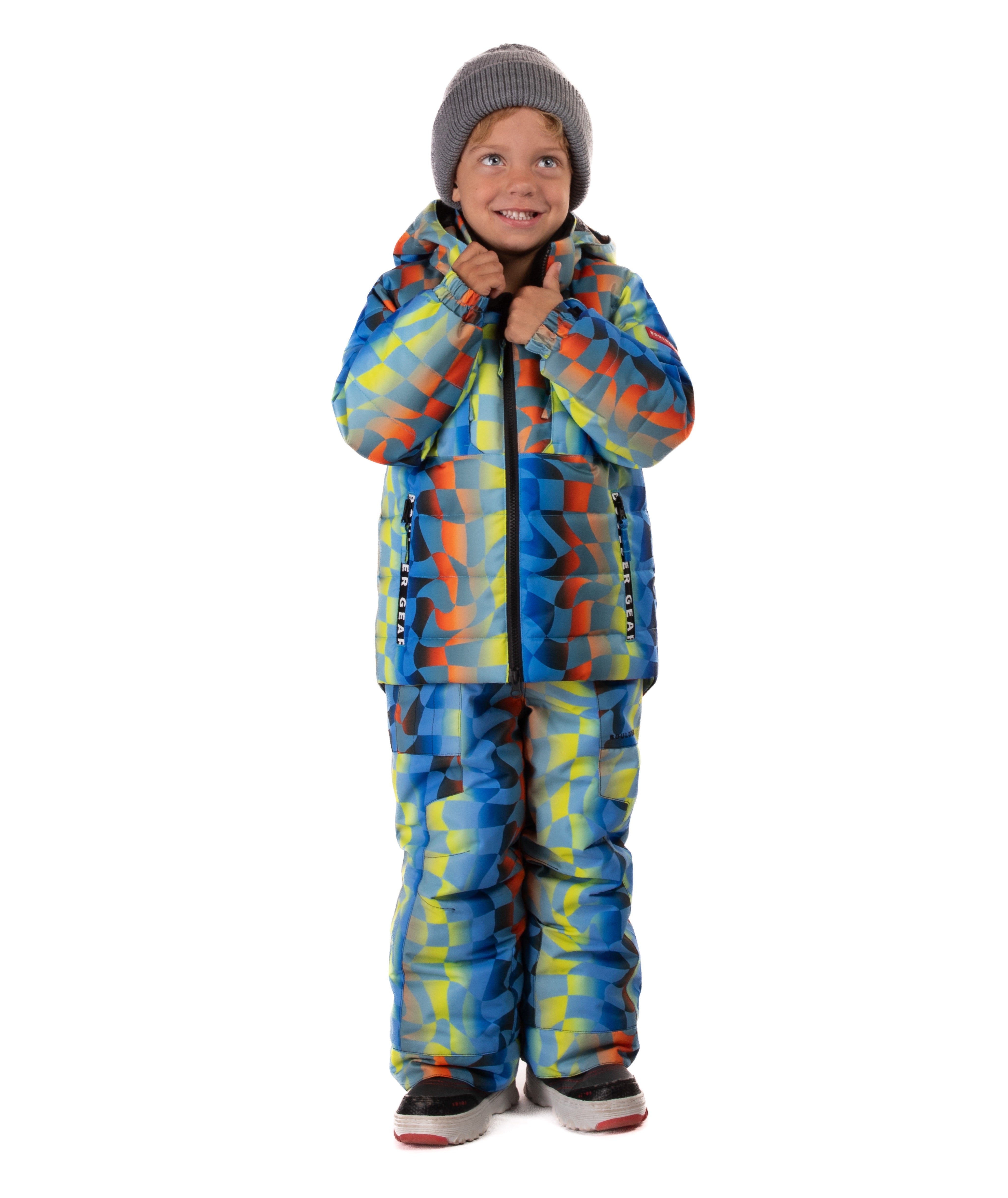 Child wearing a yellow, blue, and orange multi color geometric print quilted winter jacket with chest pockets and hand-warmer pockets on a white background