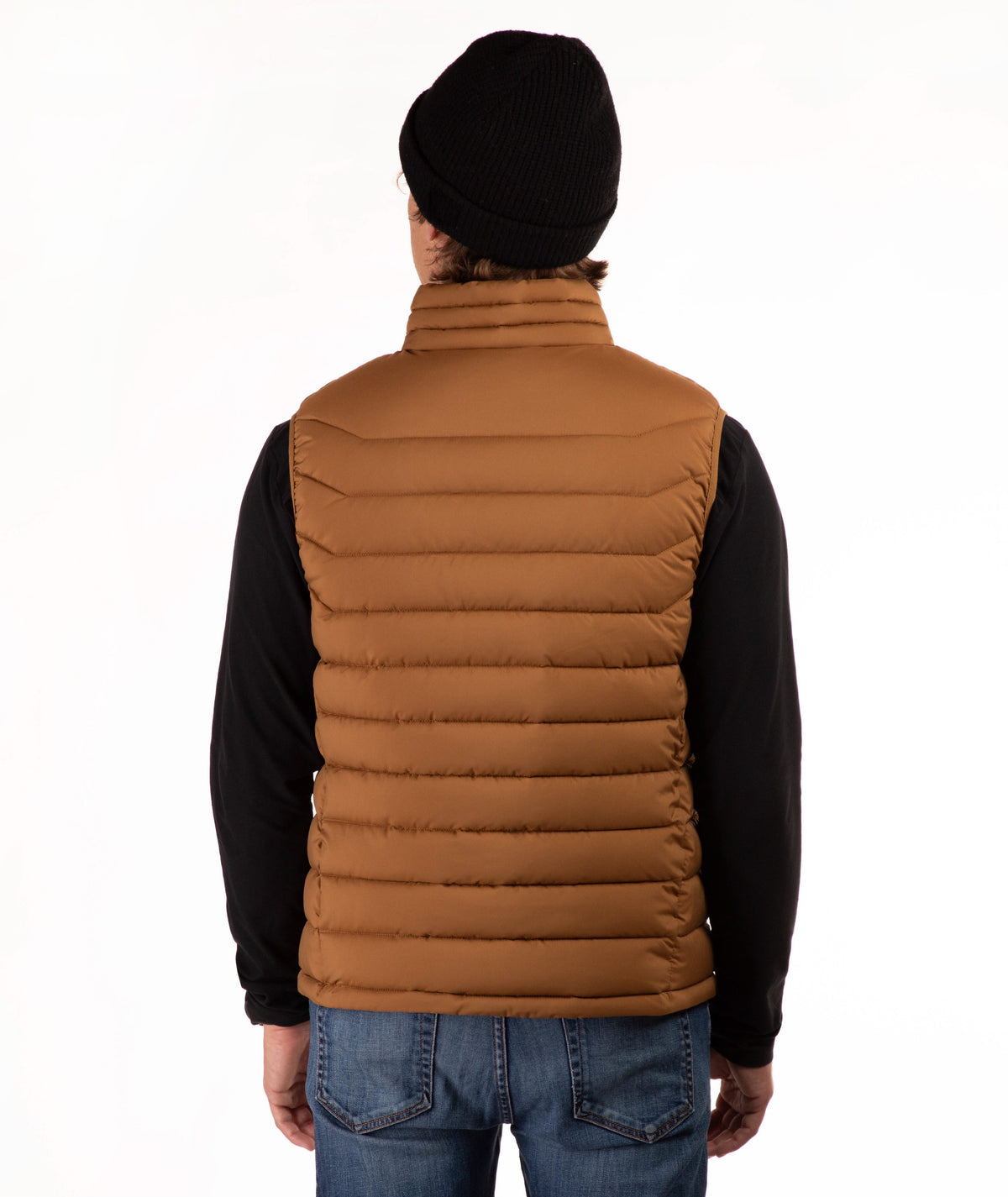A man viewed from behind wearing a brown quilted puffer vest over a black long-sleeve shirt, blue jeans, and a black beanie, against a plain white background.
