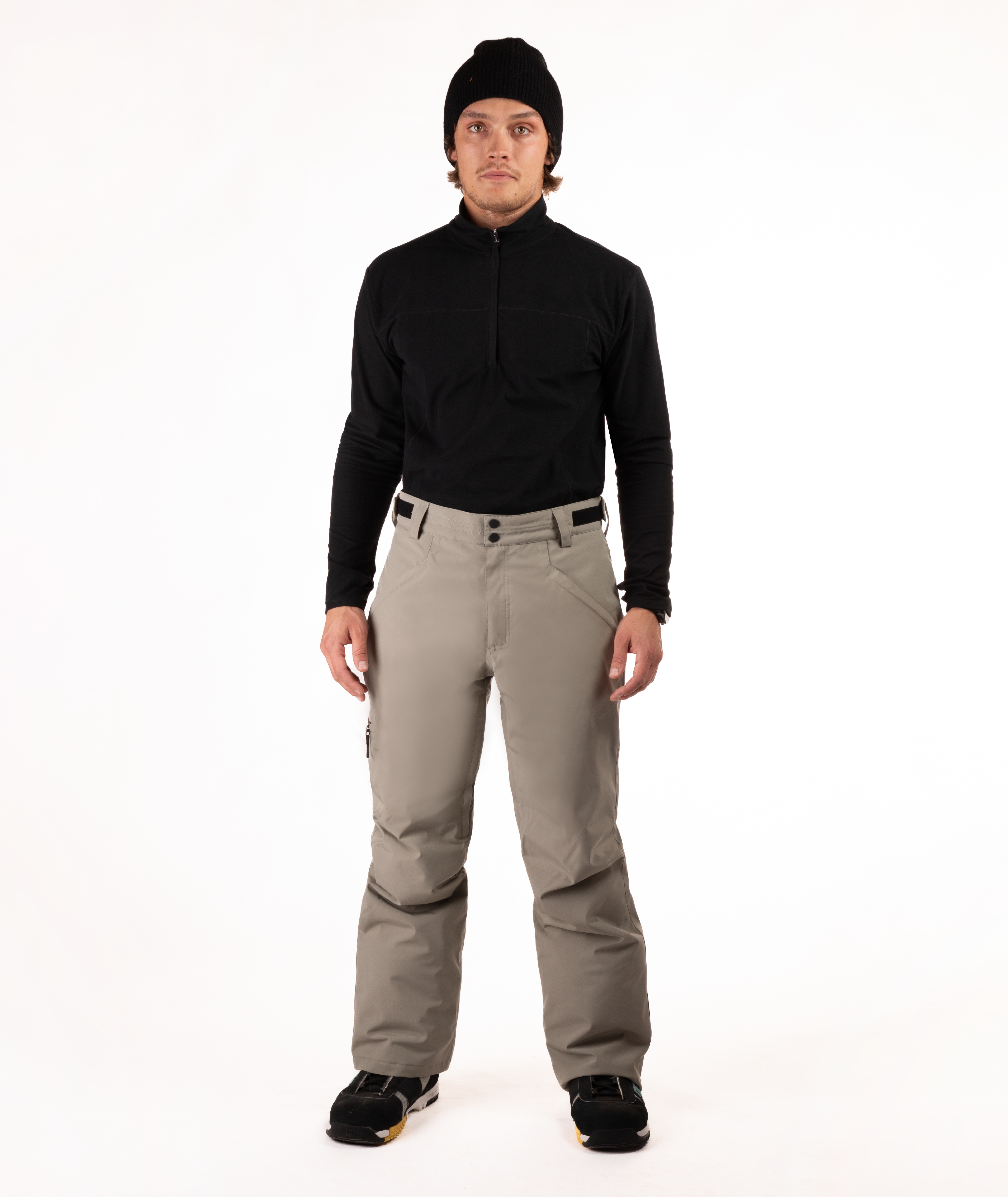 Person wearing a black top and beige snow pants on a white background