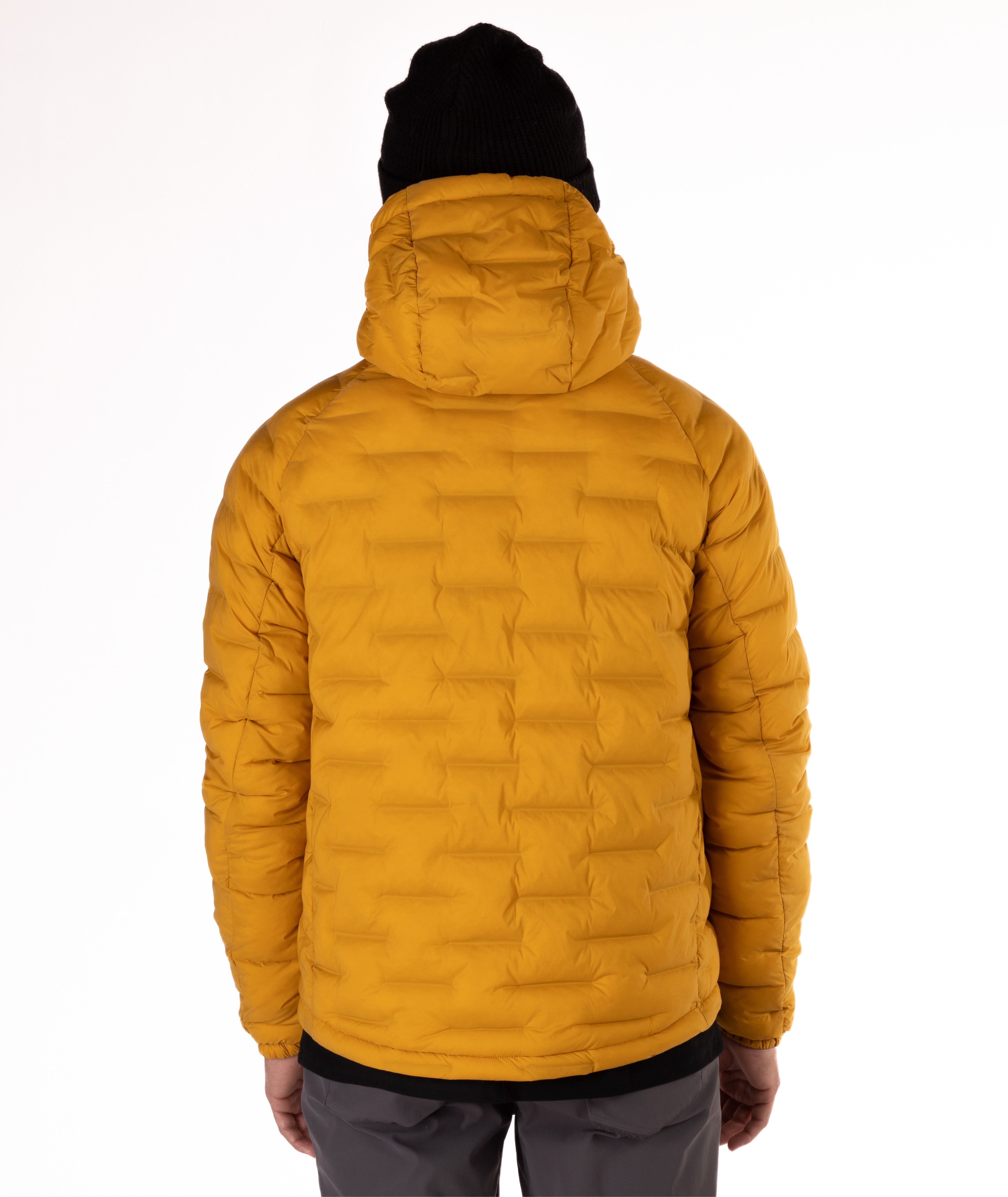 Person wearing a mustard yellow puffer jacket with a black zipper on a white background