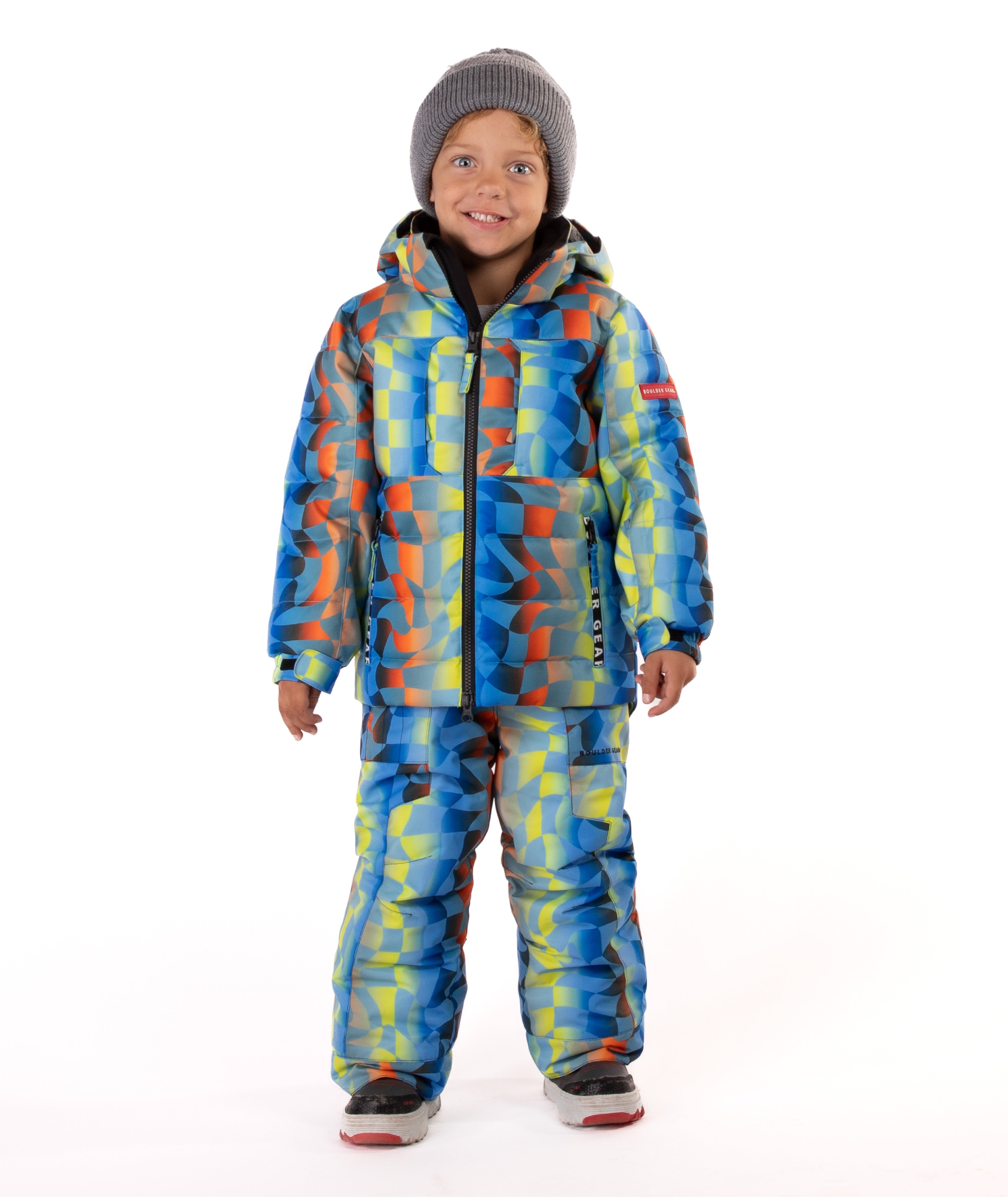 Child wearing a yellow, blue, and orange multi color geometric print quilted winter jacket with chest pockets and hand-warmer pockets on a white background