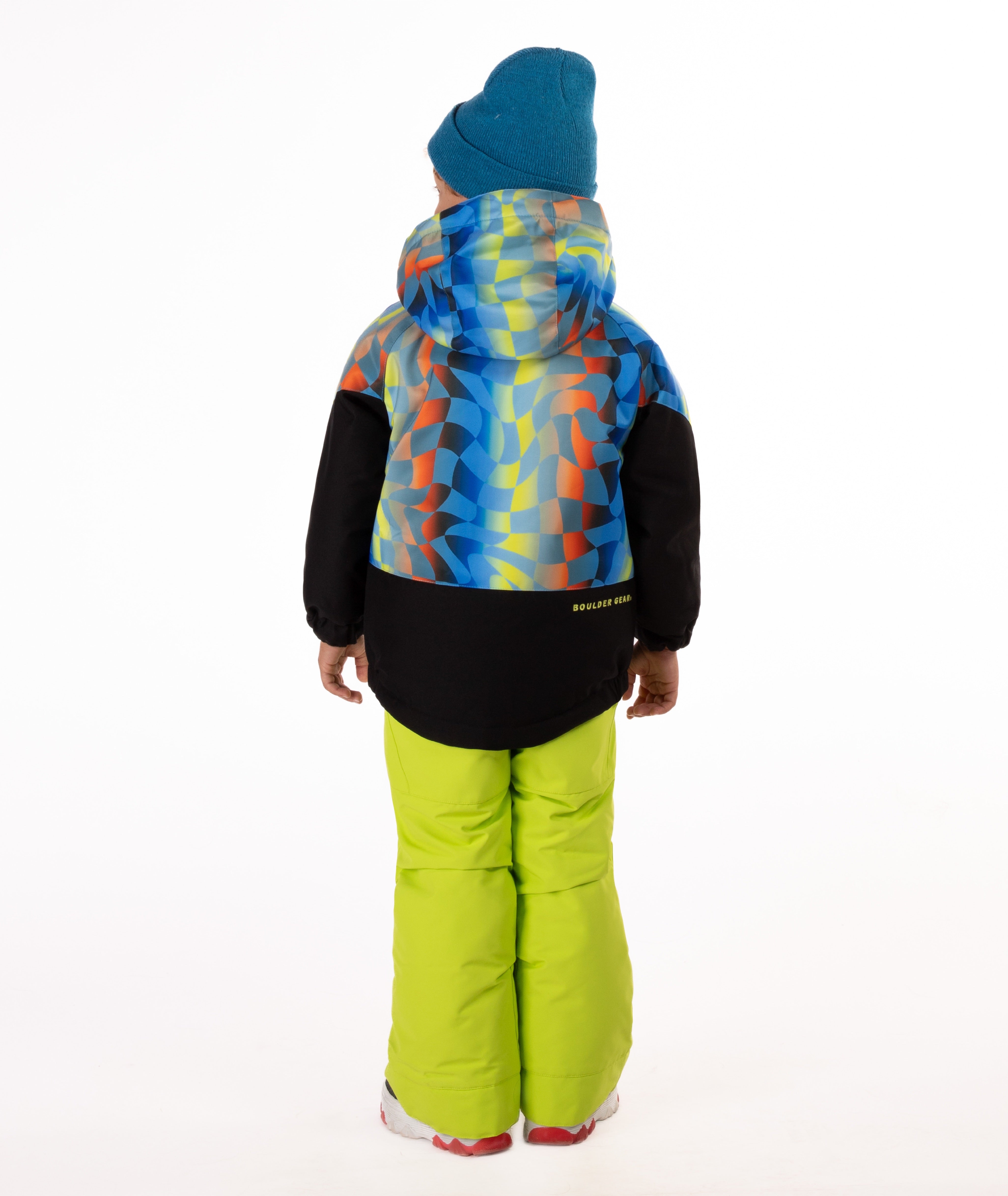 Child wearing a two-tone jacket with a geometric multi-color print on the top and black on the bottom of the jacket showing the back of the jacket with a visible Boulder Gear brand logo