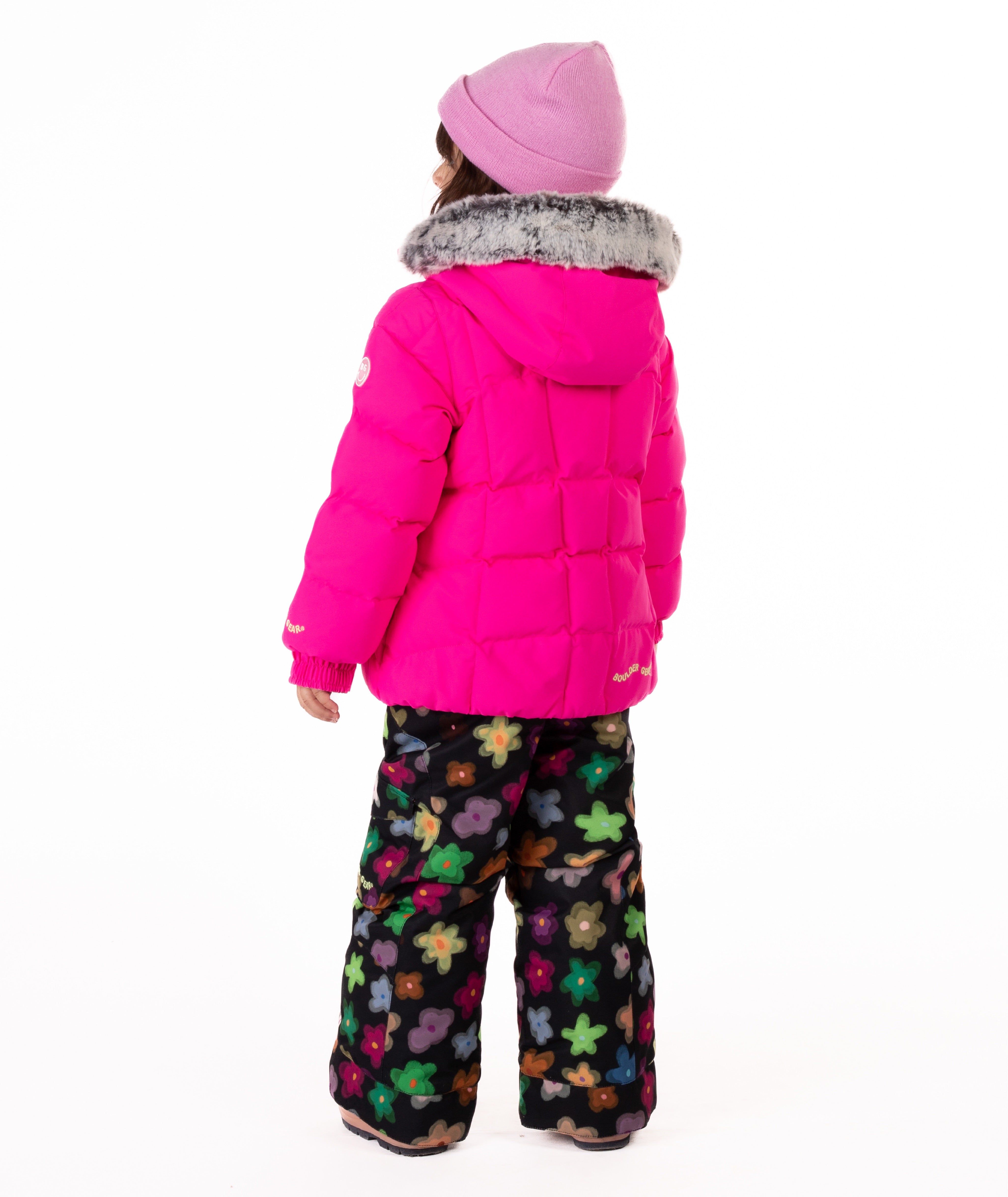 Child wearing a bright pink quilted puffy winter coat on a white background