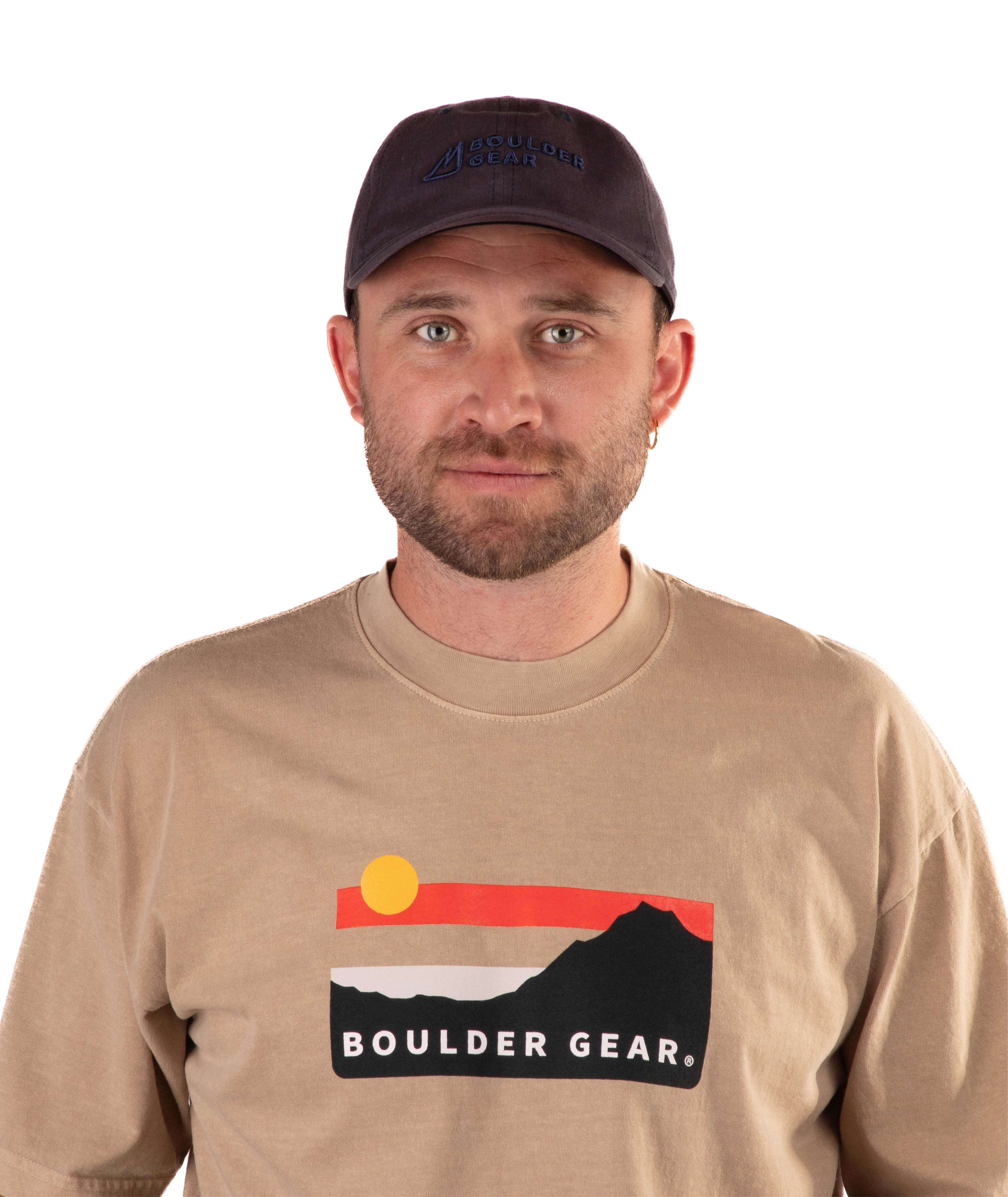 Man wearing a brown Boulder Gear t-shirt and navy cap on a white background