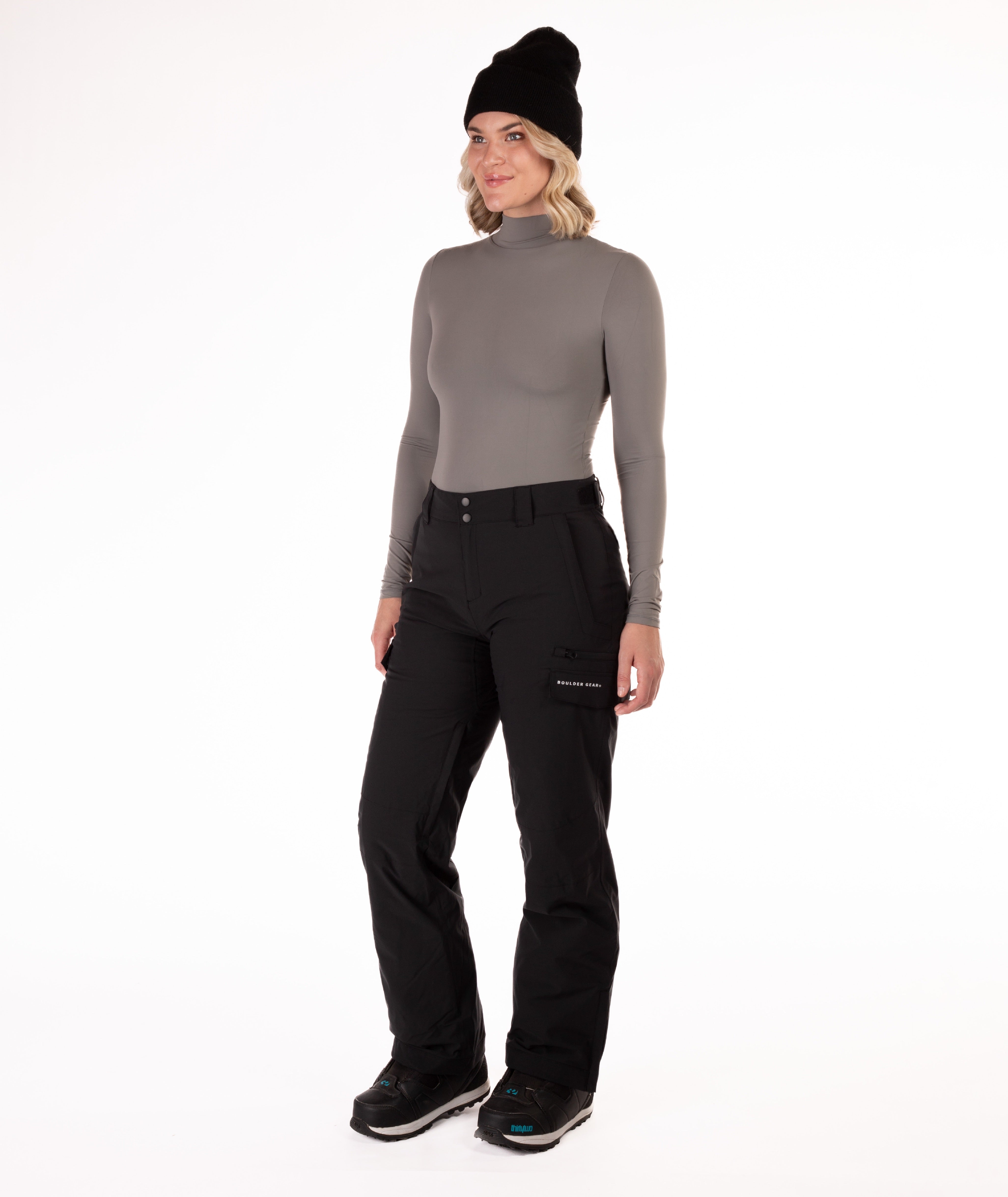 Person wearing a gray long-sleeve top and black snow pants on a white background