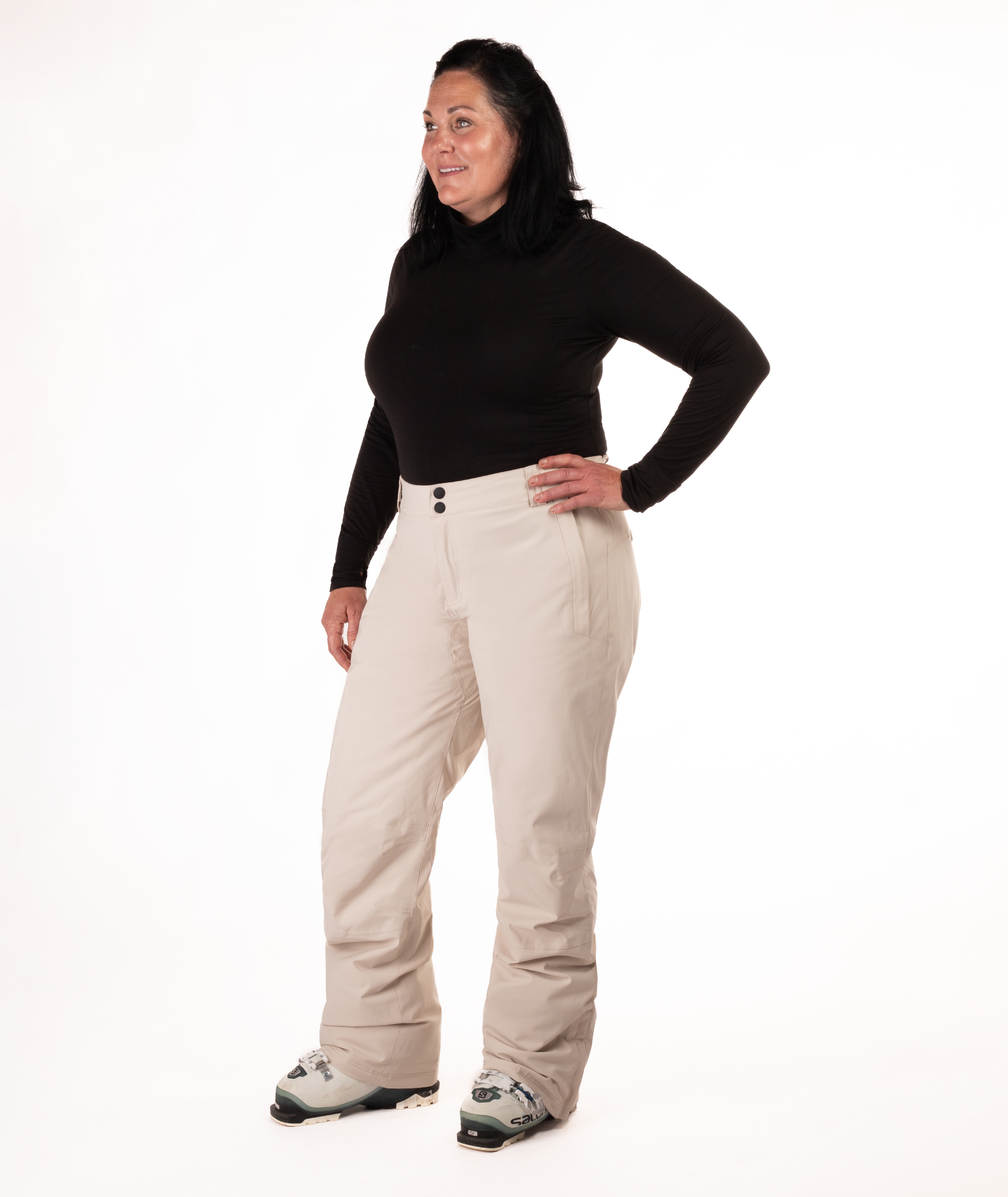 Person wearing a black long-sleeve top and beige snow pants on a white background