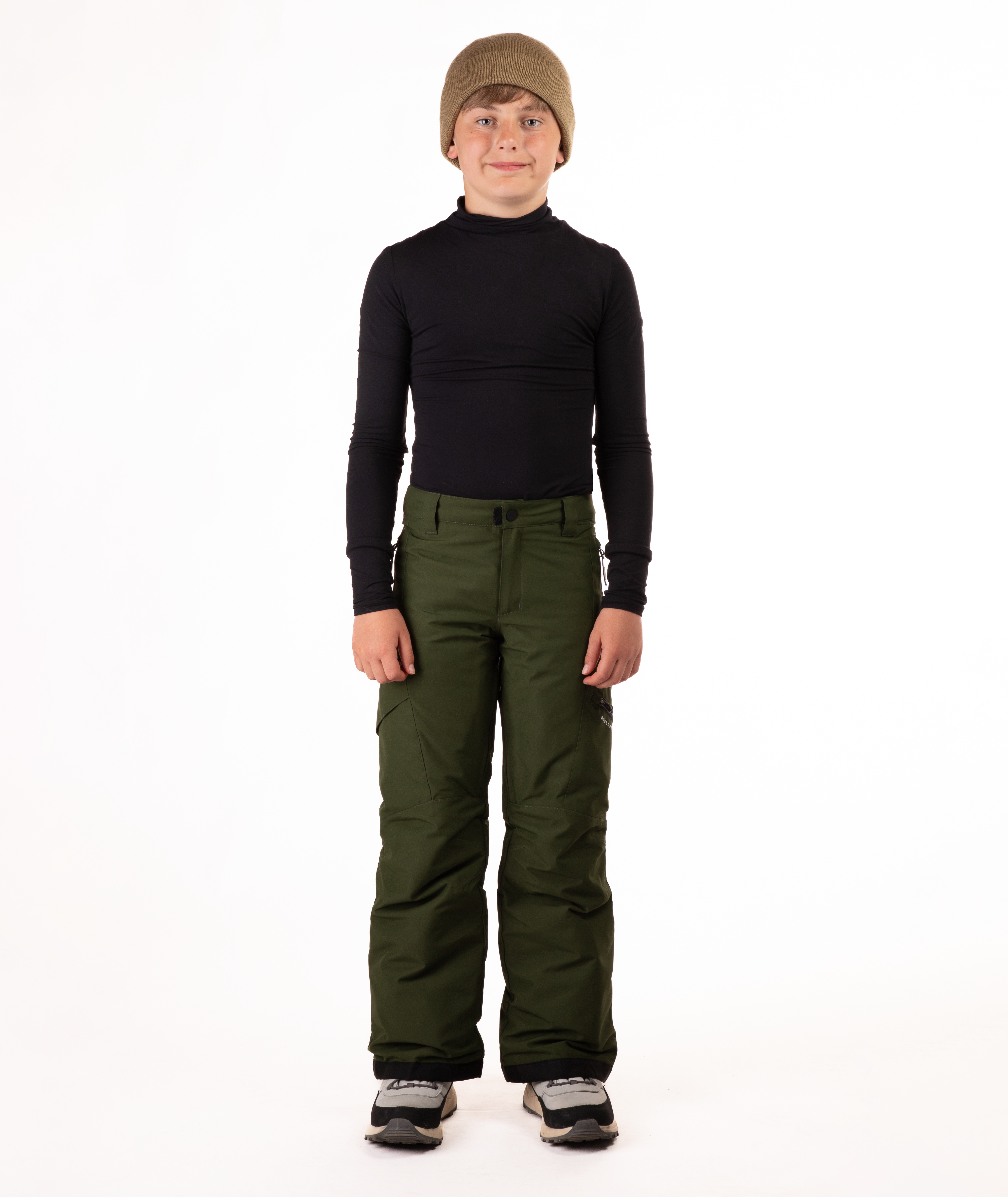youth boy wearing a black long-sleeve shirt and green snow pants on a white background