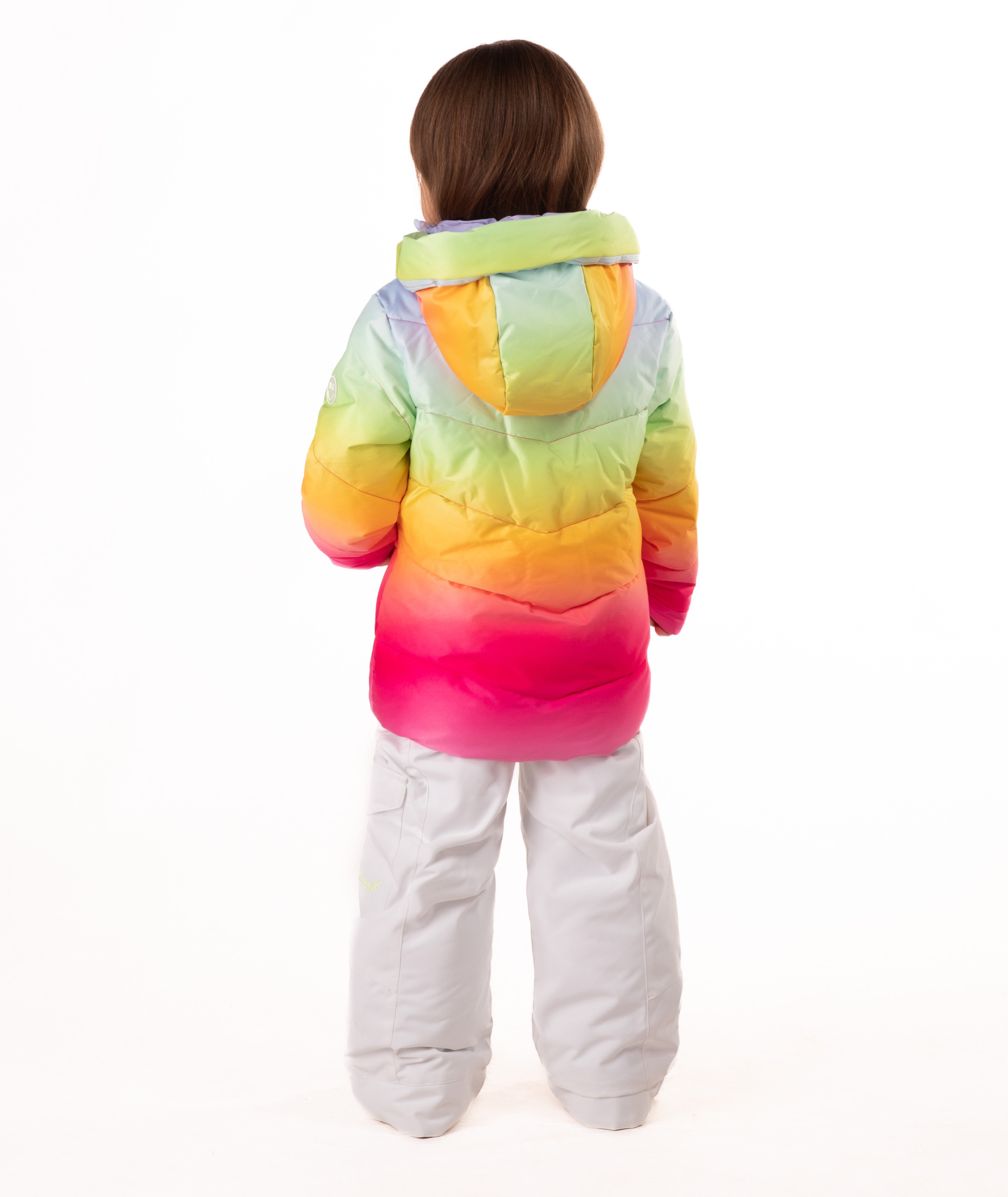 back of a child wearing a colorful gradient jacket and white pants on a white background