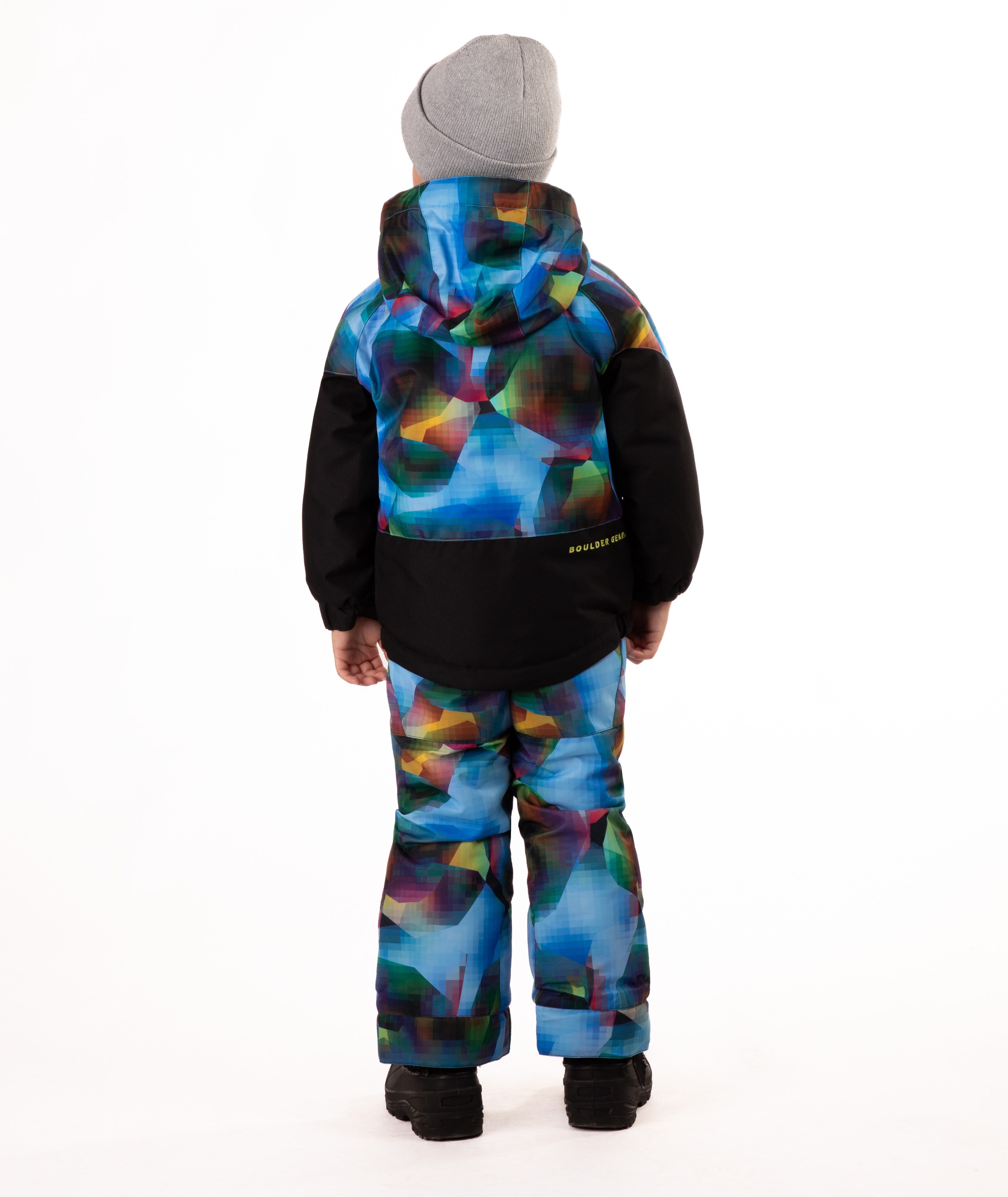 Child wearing a two-tone jacket with black on the bottom half and multi tone blue printed top half on a white background showing a visible Boulder Gear brand logo on the center back of the jacket