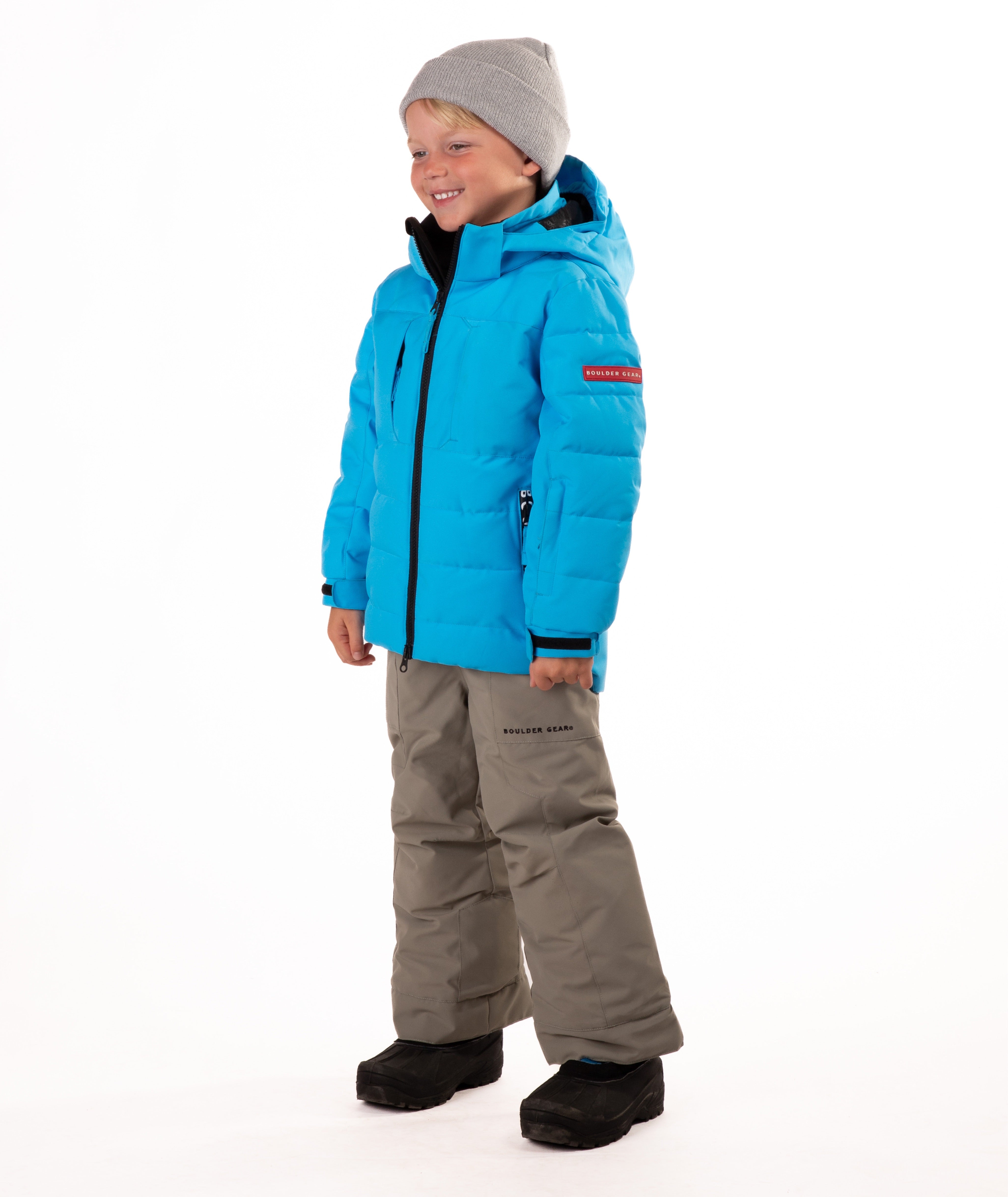Child wearing a blue quilted winter jacket with chest pockets and hand-warmer pockets on a white background
