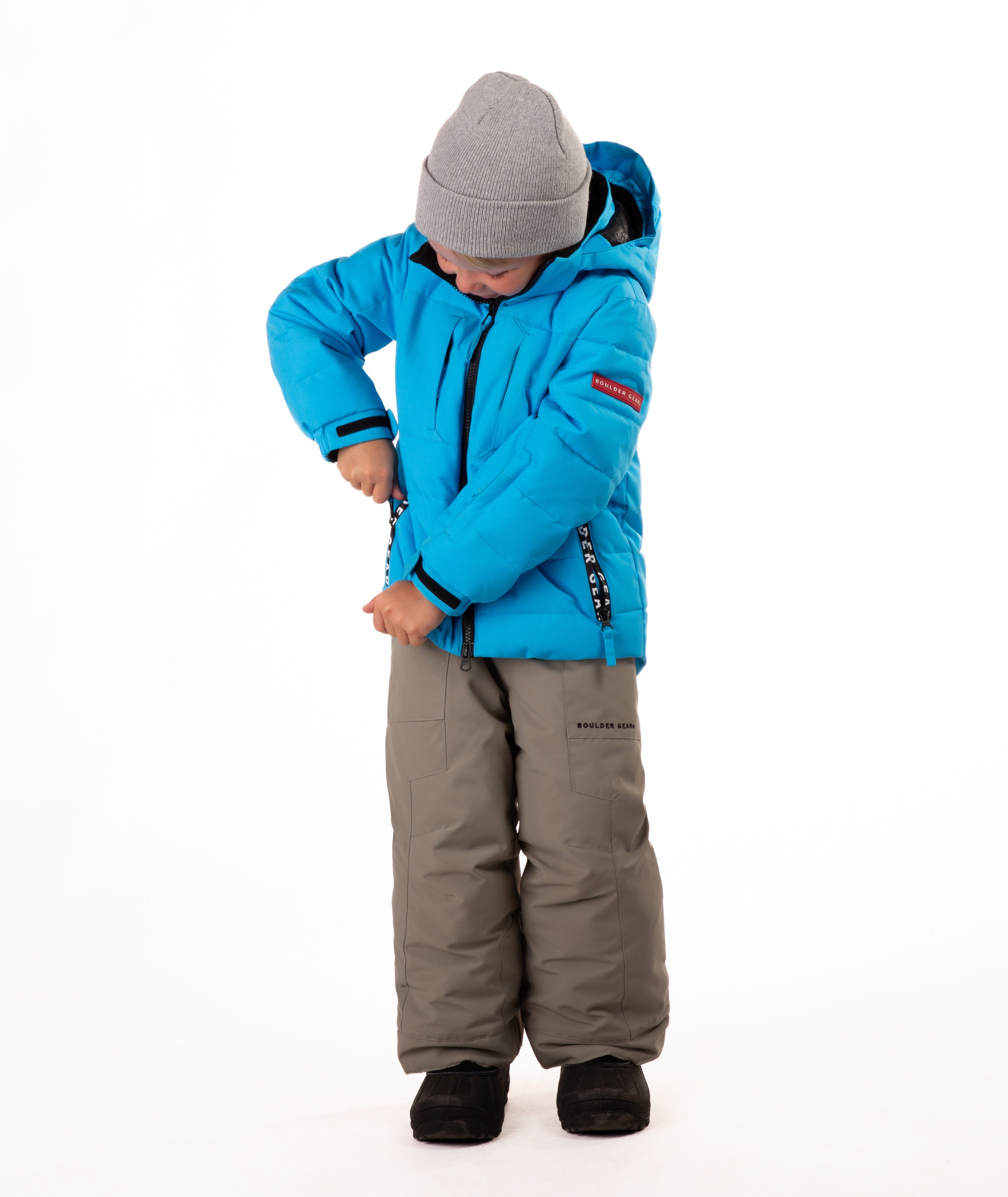 Child wearing a blue quilted winter jacket with chest pockets and hand-warmer pockets on a white background