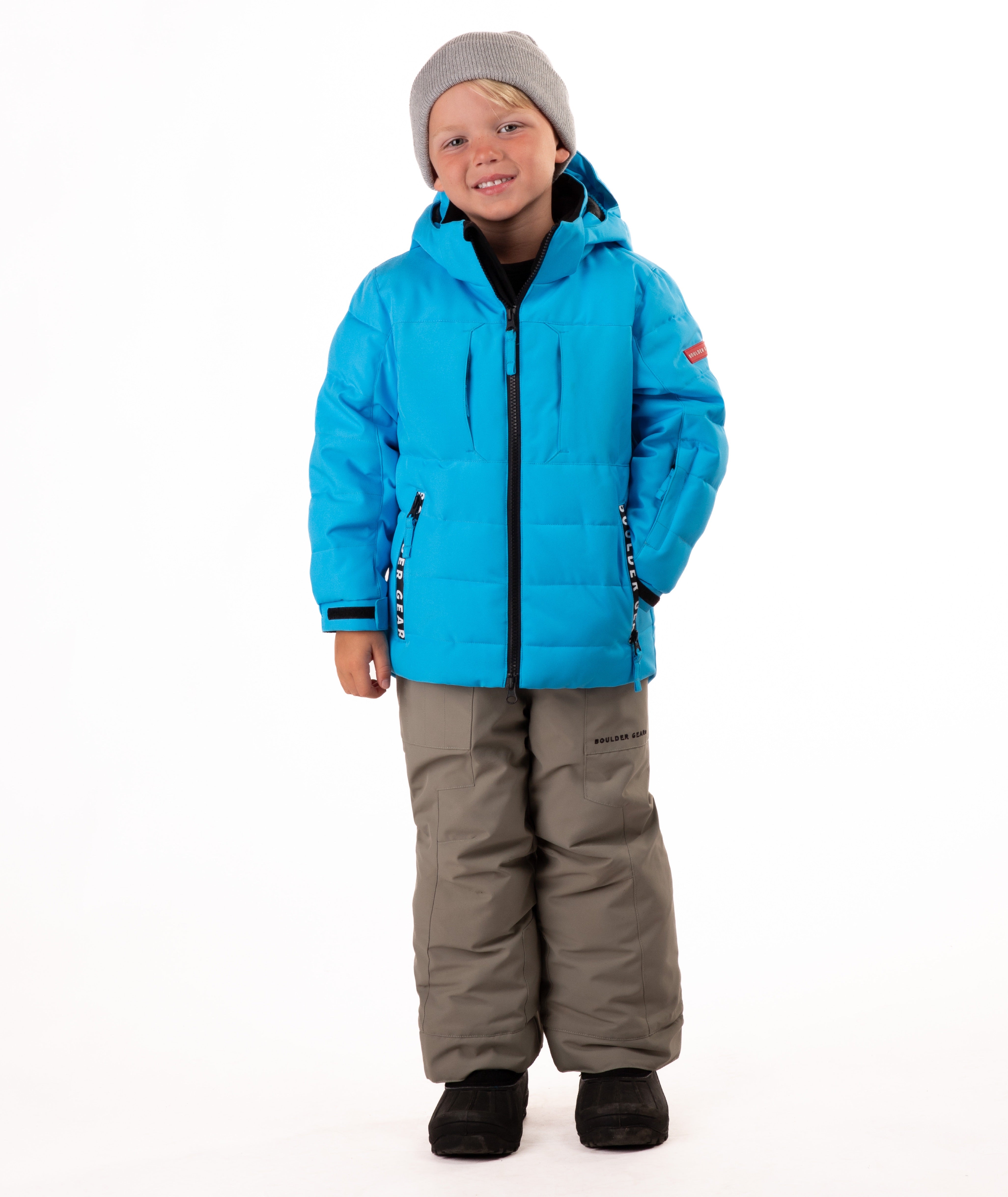 Child wearing a blue quilted winter jacket with chest pockets and hand-warmer pockets on a white background