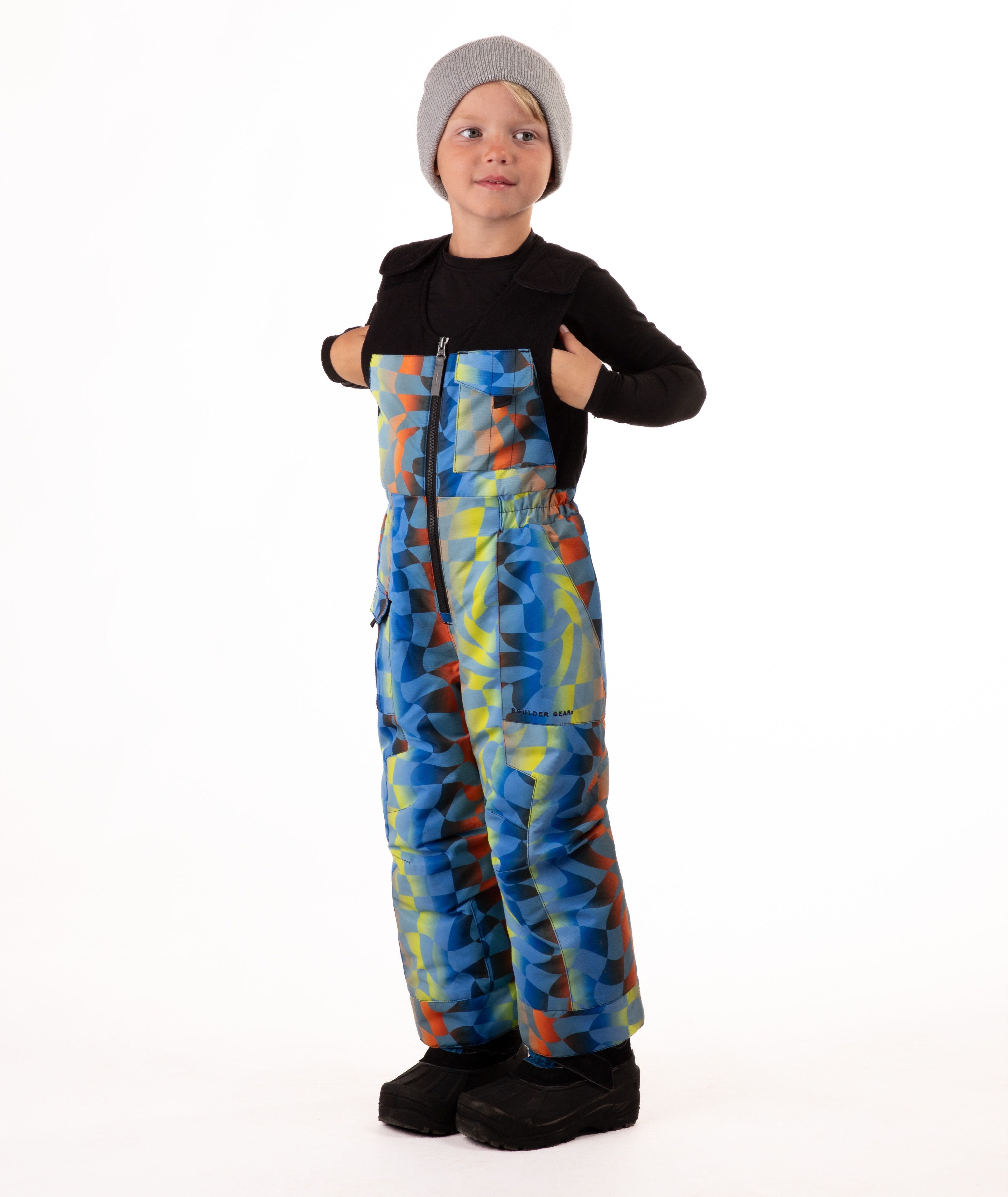Child wearing colorful geometric print snow bibs on a white background
