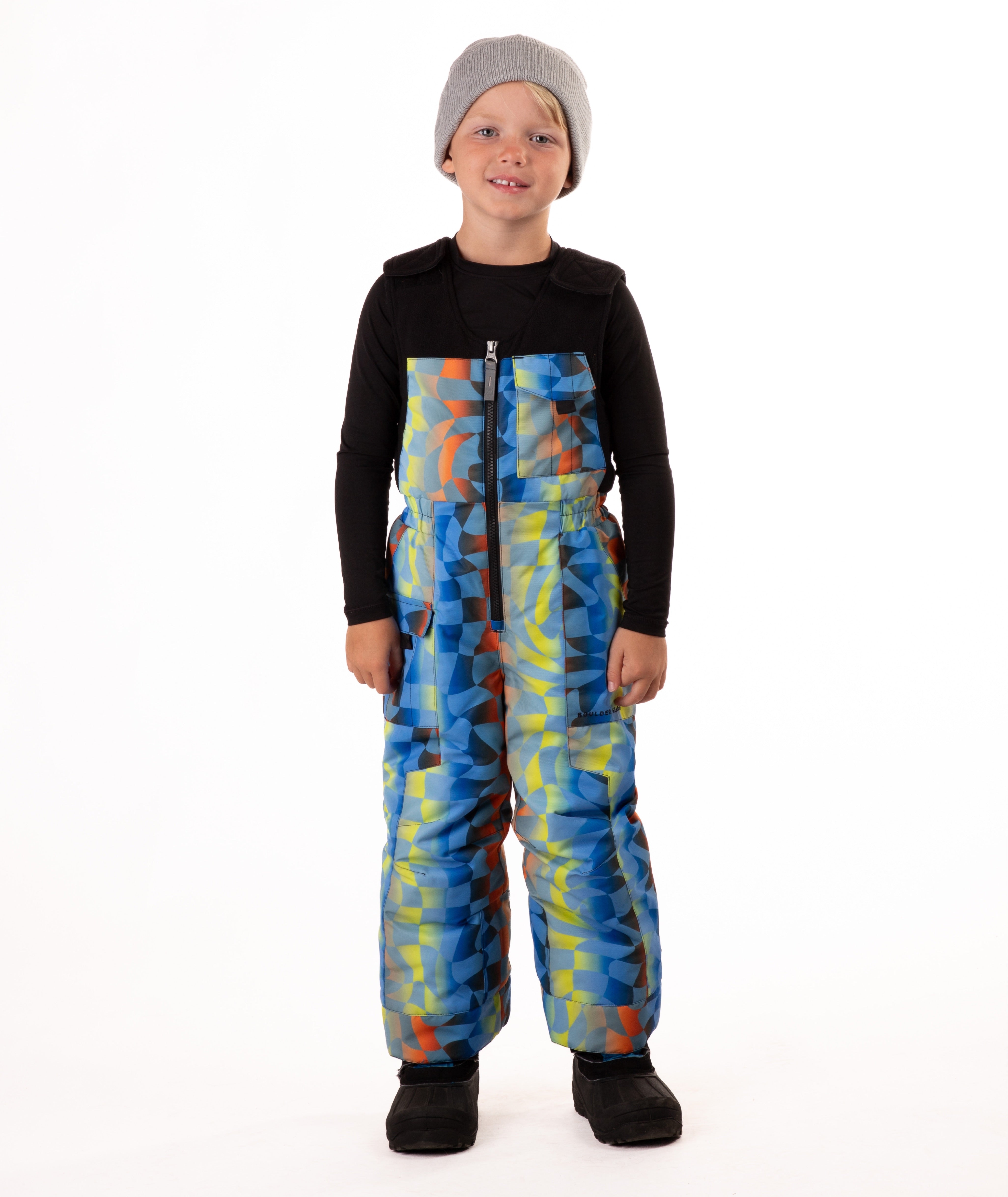 Child wearing colorful geometric print snow bibs on a white background