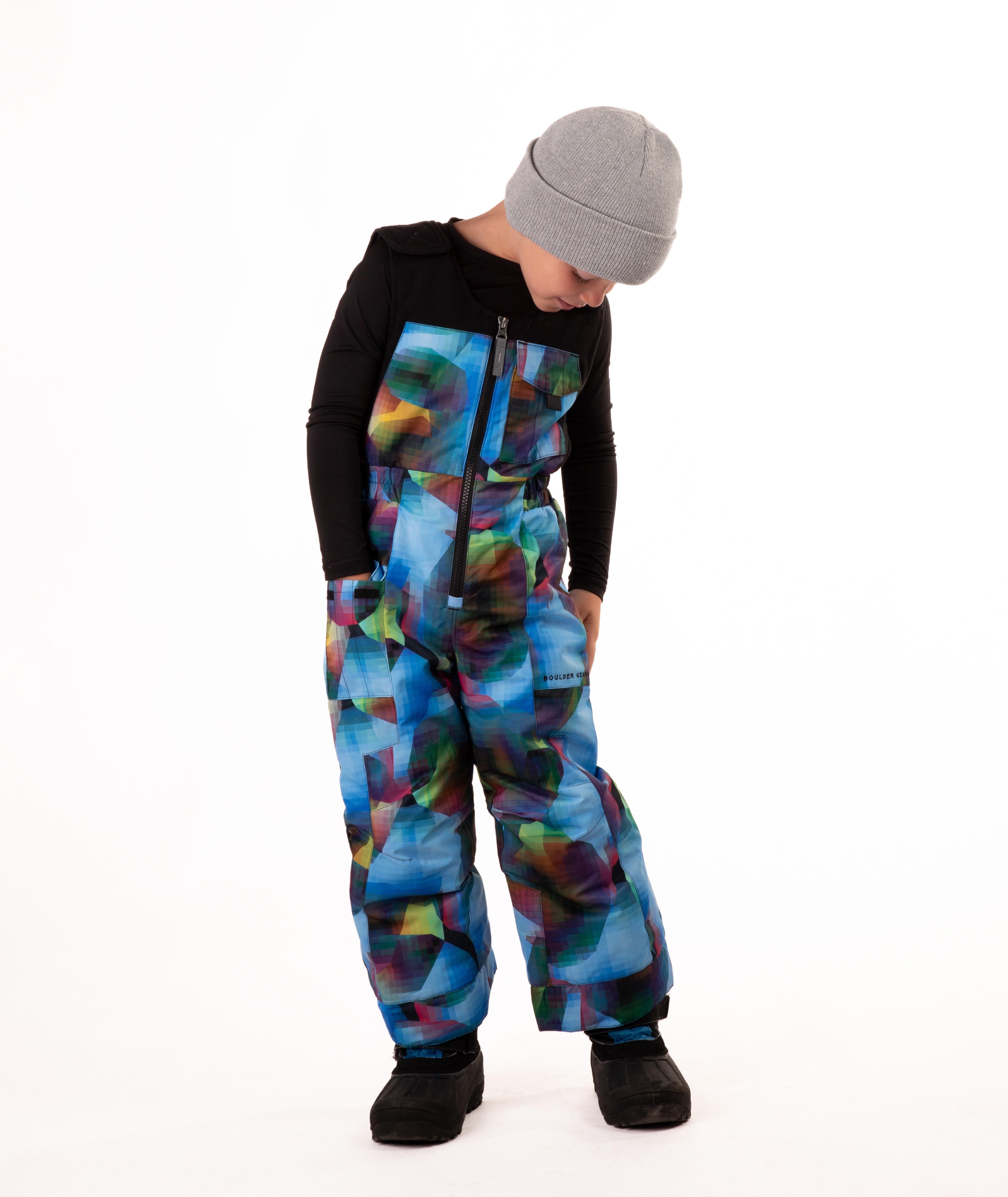 Child wearing colorful geometric print snow bibs on a white background