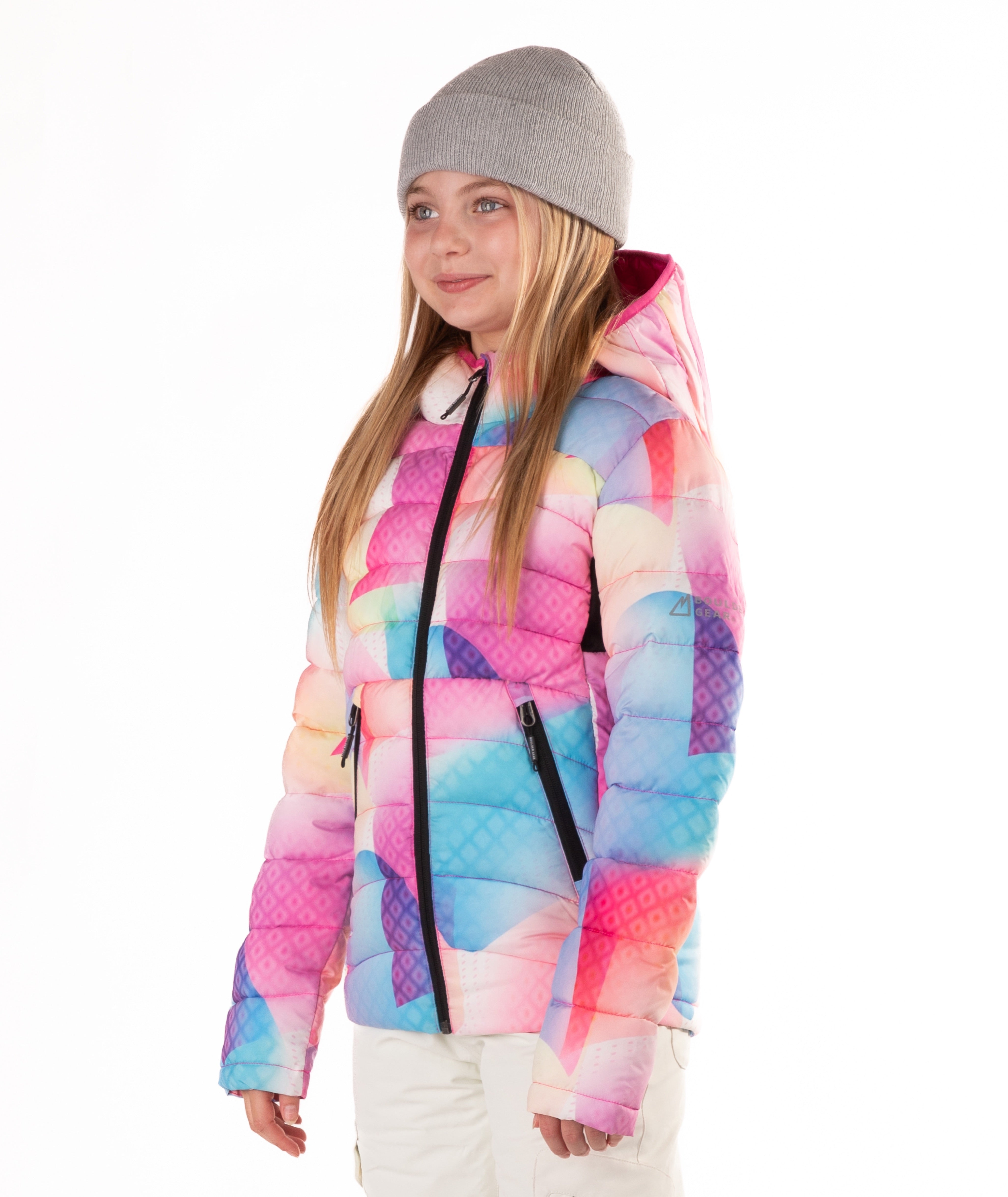 girl wearing a multi colored abstract pastel patterned puffer jacket on a white background