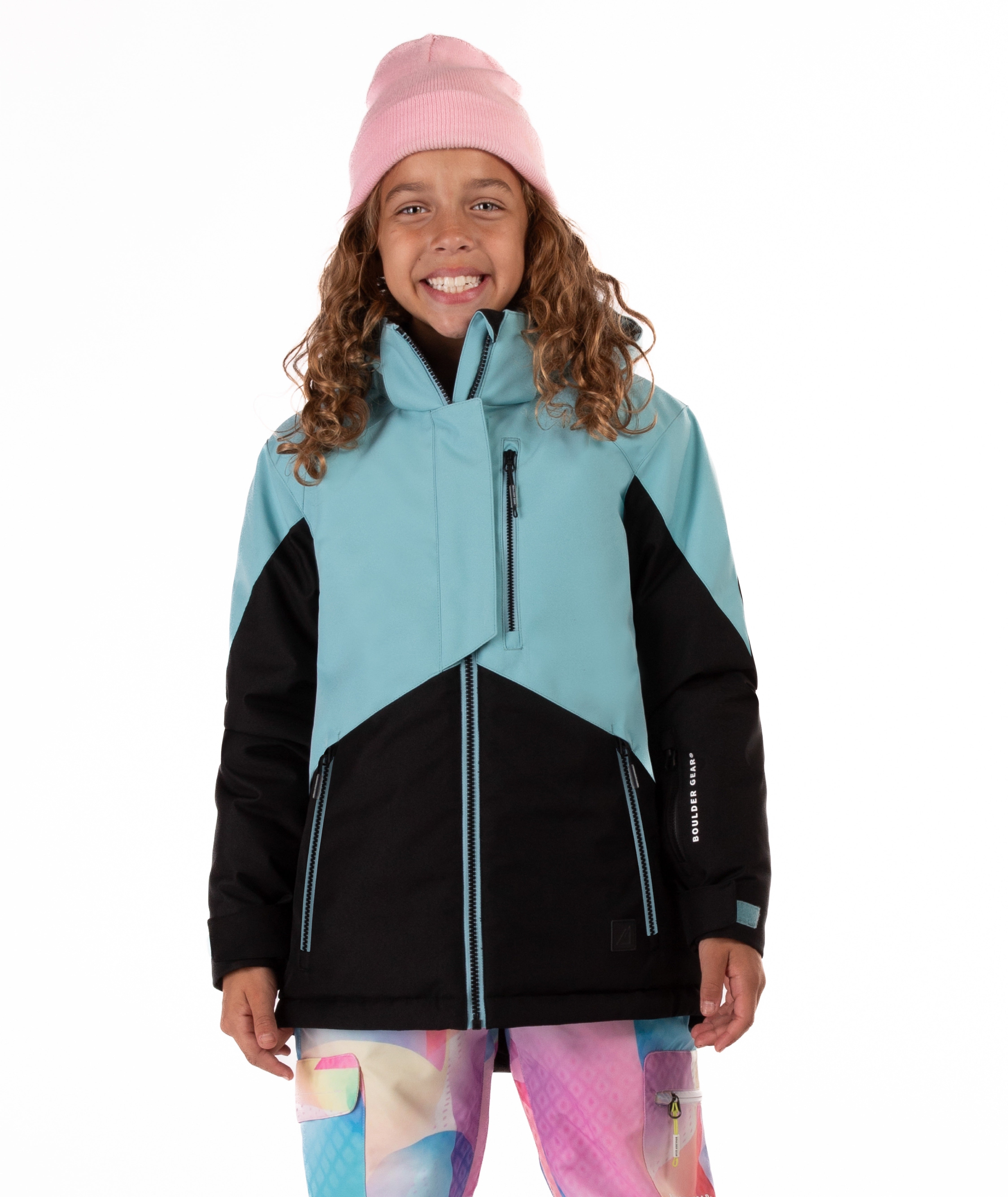 Youth girl wearing a teal and black jacket with contrast zippers on a white background