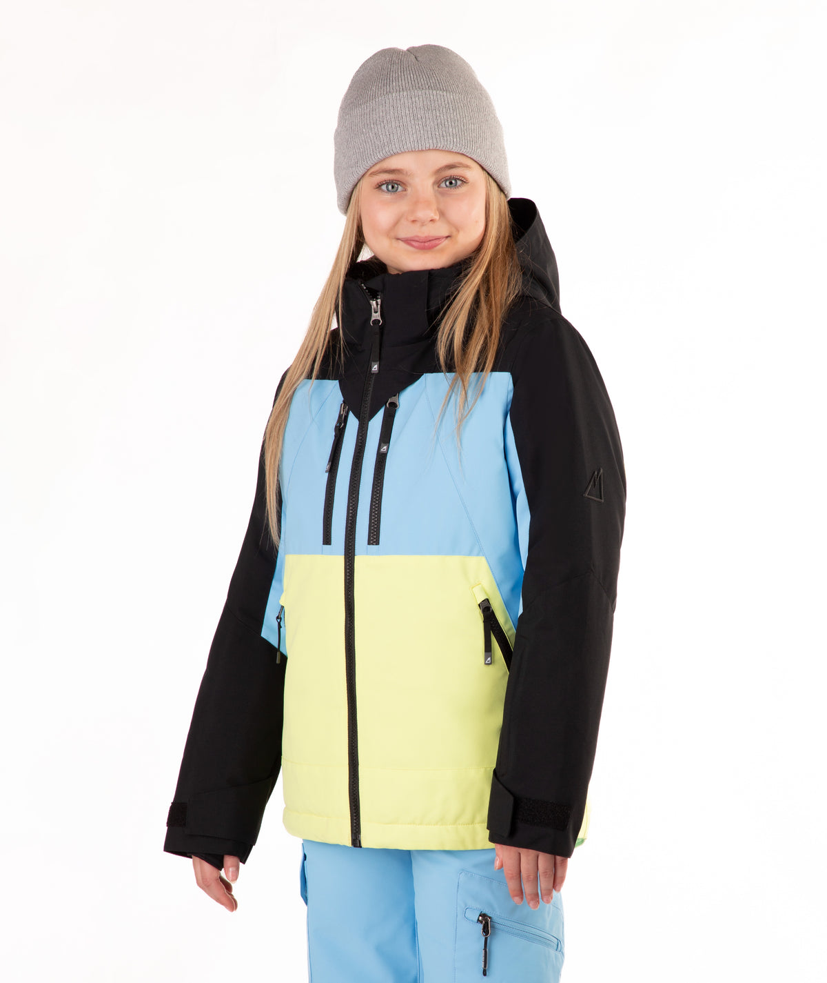 A young girl wearing a color-blocked ski jacket with black sleeves, a light blue upper chest, and a bright yellow lower front panel, paired with light blue ski pants and a gray beanie, against a plain white background.