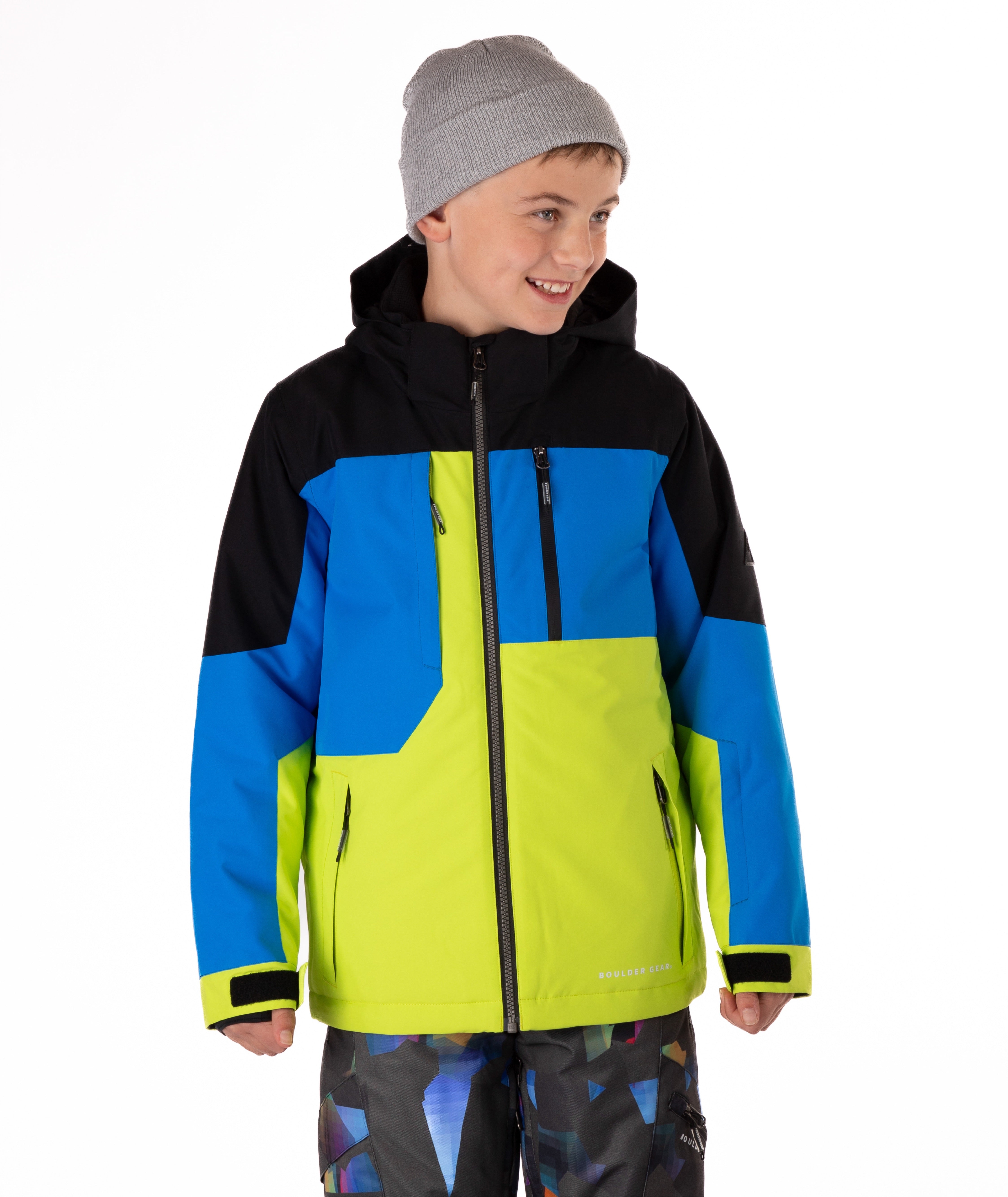Boy wearing a colorful jacket with black, blue, and green sections on a white background