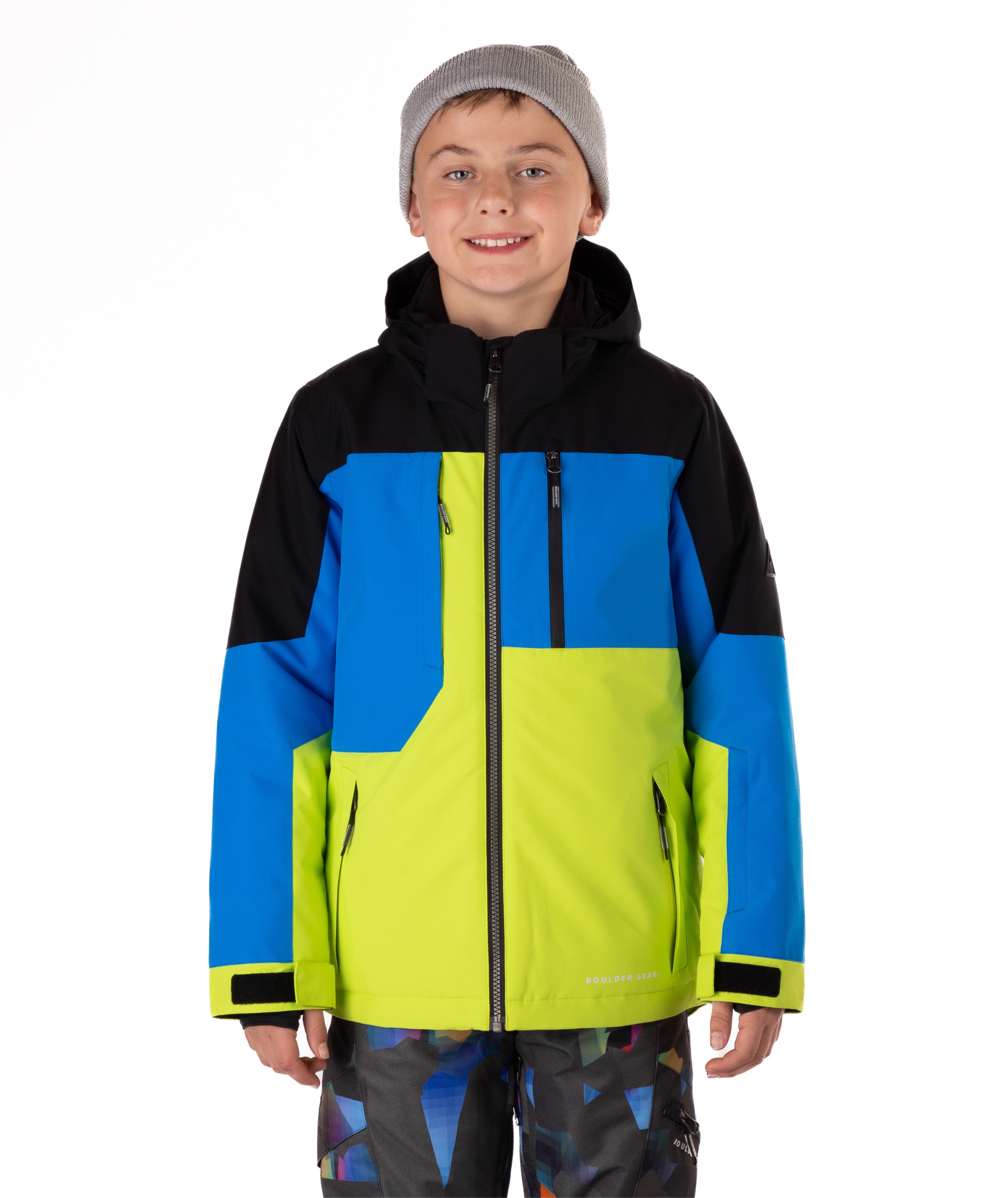 Boy wearing a colorful jacket with blue, green, and black sections on a white background