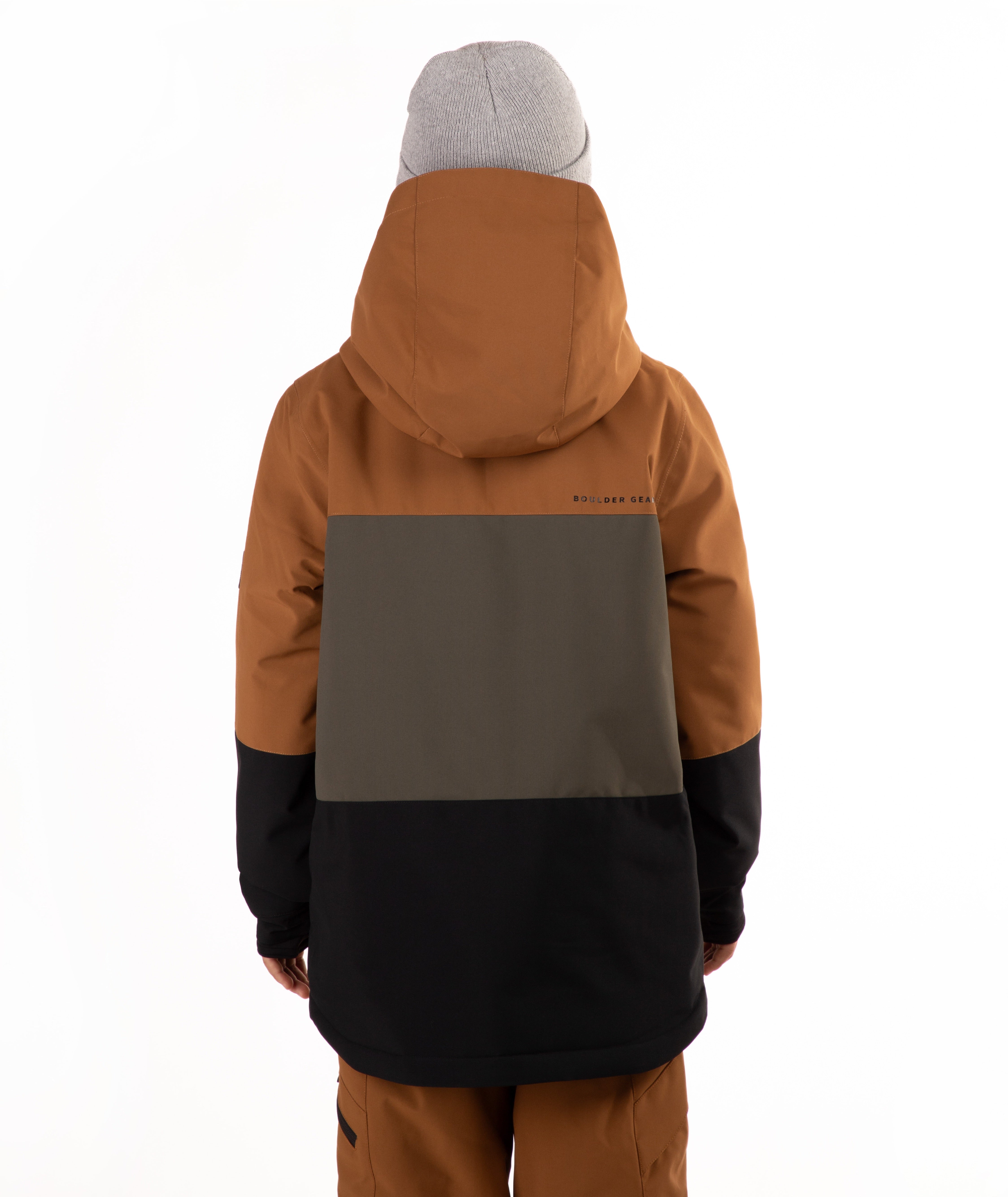 A child wearing a color-blocked ski jacket in brown, green, and black, paired with brown pants and a gray beanie, photographed against a solid white background.