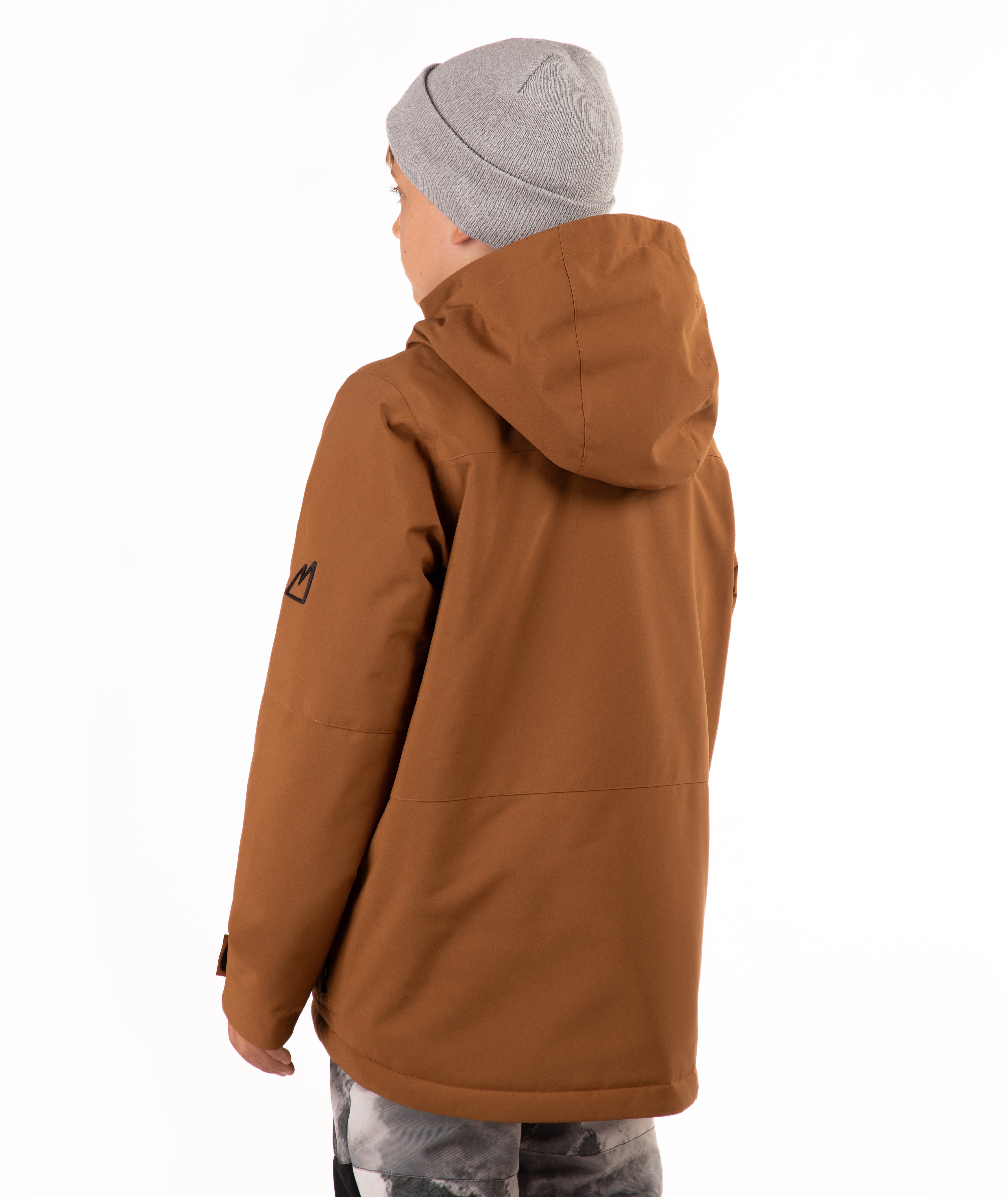 A child wearing a brown hooded snowboard jacket with black zippers, a gray beanie, and patterned pants, standing against a plain white background.