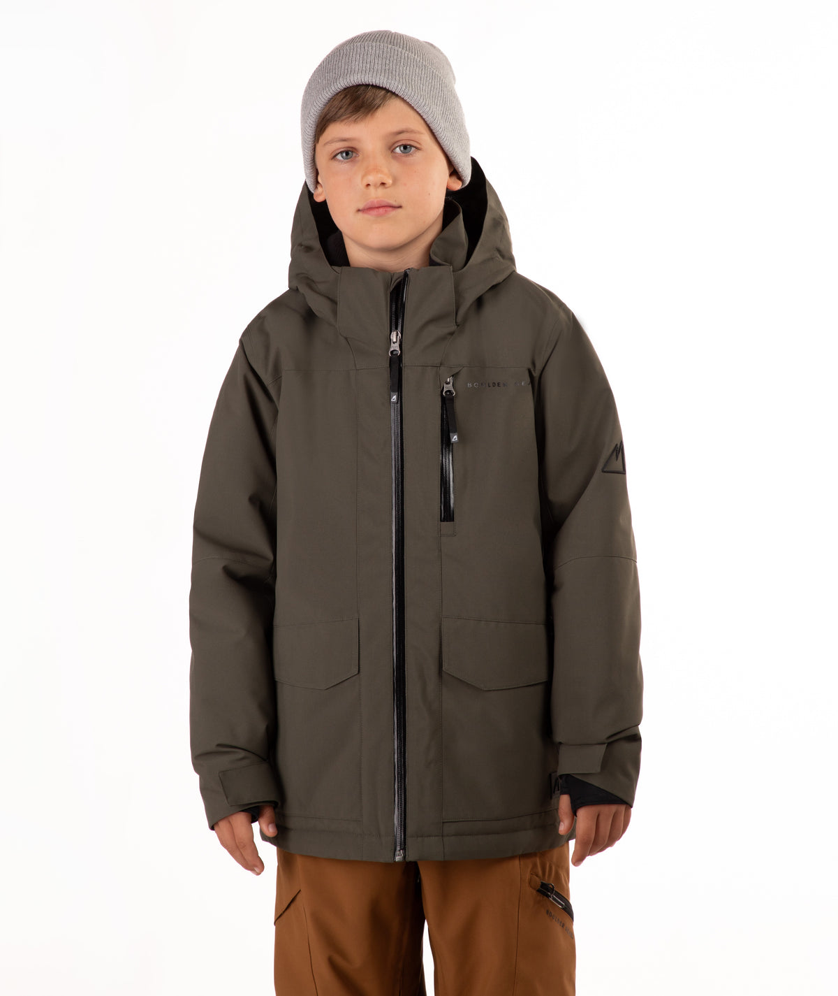 A child wearing a dark olive green hooded snowboard jacket, brown pants, and a gray beanie, standing against a plain white background.