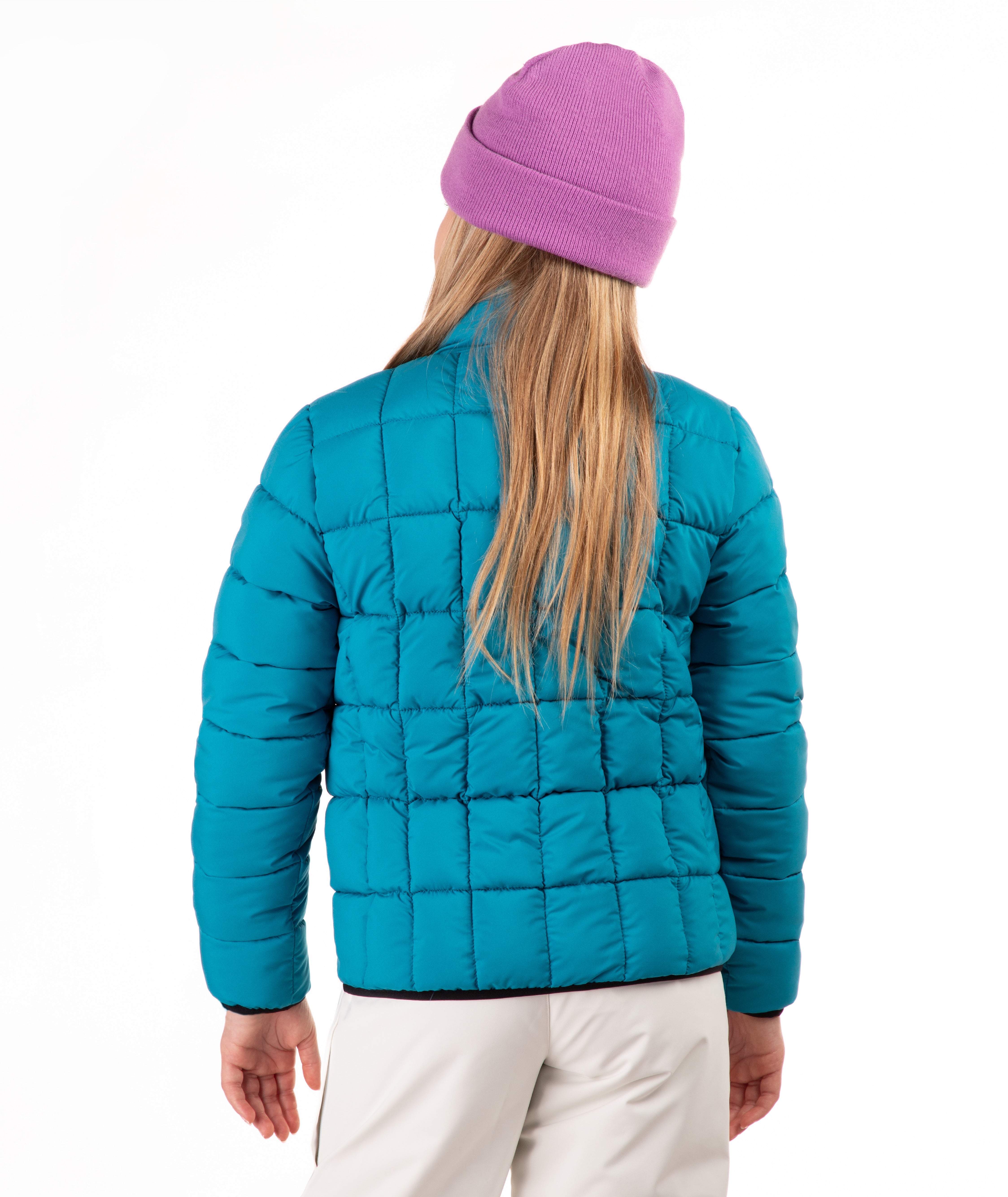 A child shown from the back wearing a bright turquoise quilted puffer jacket, a pink knit beanie, and off-white pants against a plain white studio background.