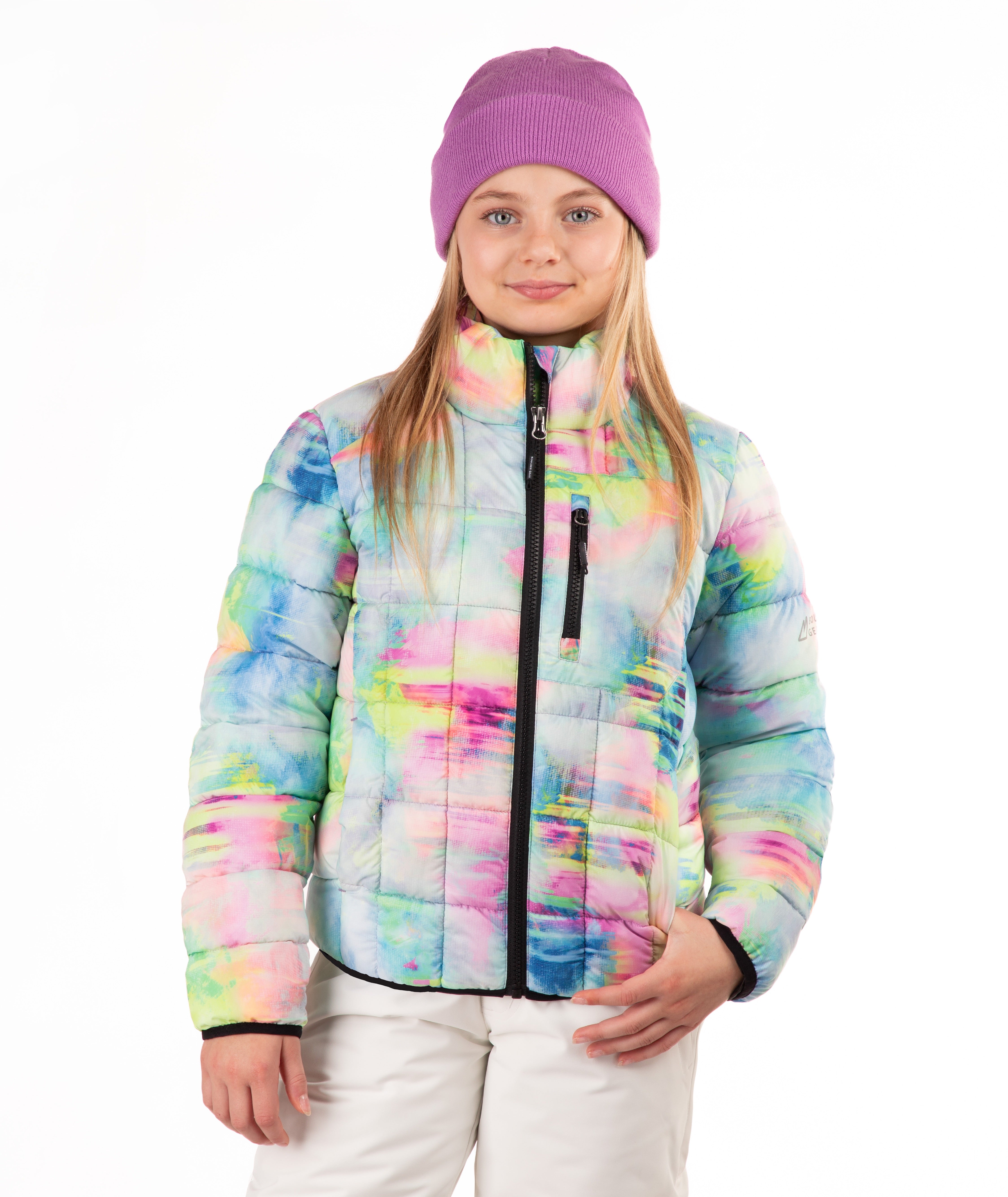 A young girl wearing a pastel tie-dye puffer jacket, a purple knit beanie, and white pants, standing against a plain white background.