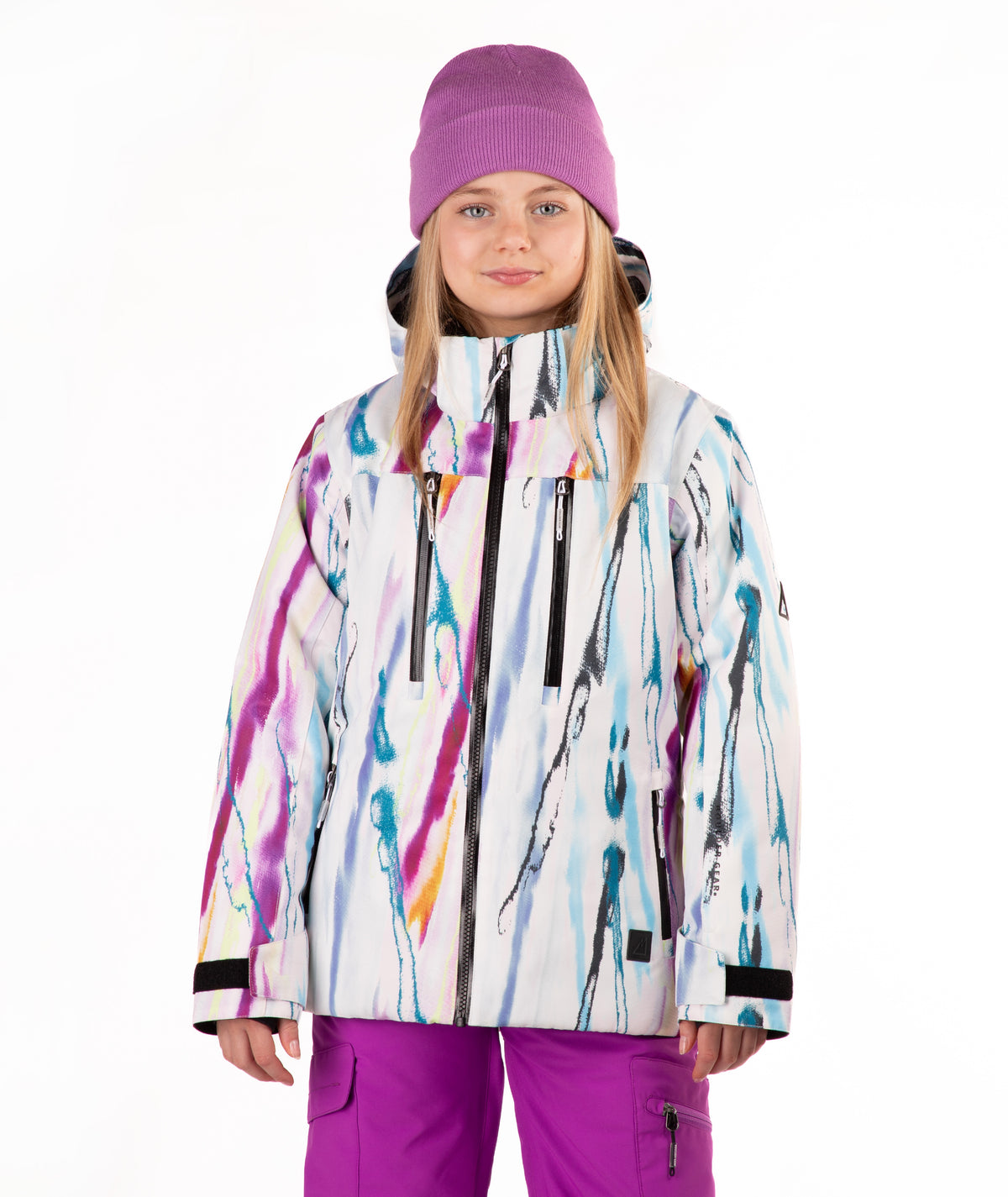 A child wearing a colorful abstract print ski jacket, a purple knit beanie, and purple ski pants, standing against a plain white studio background.