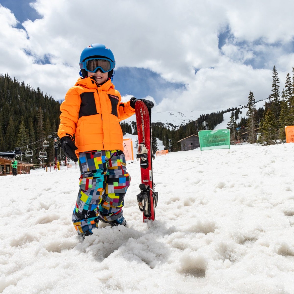 a child wearing a bright orange jacket on a snowy mountain