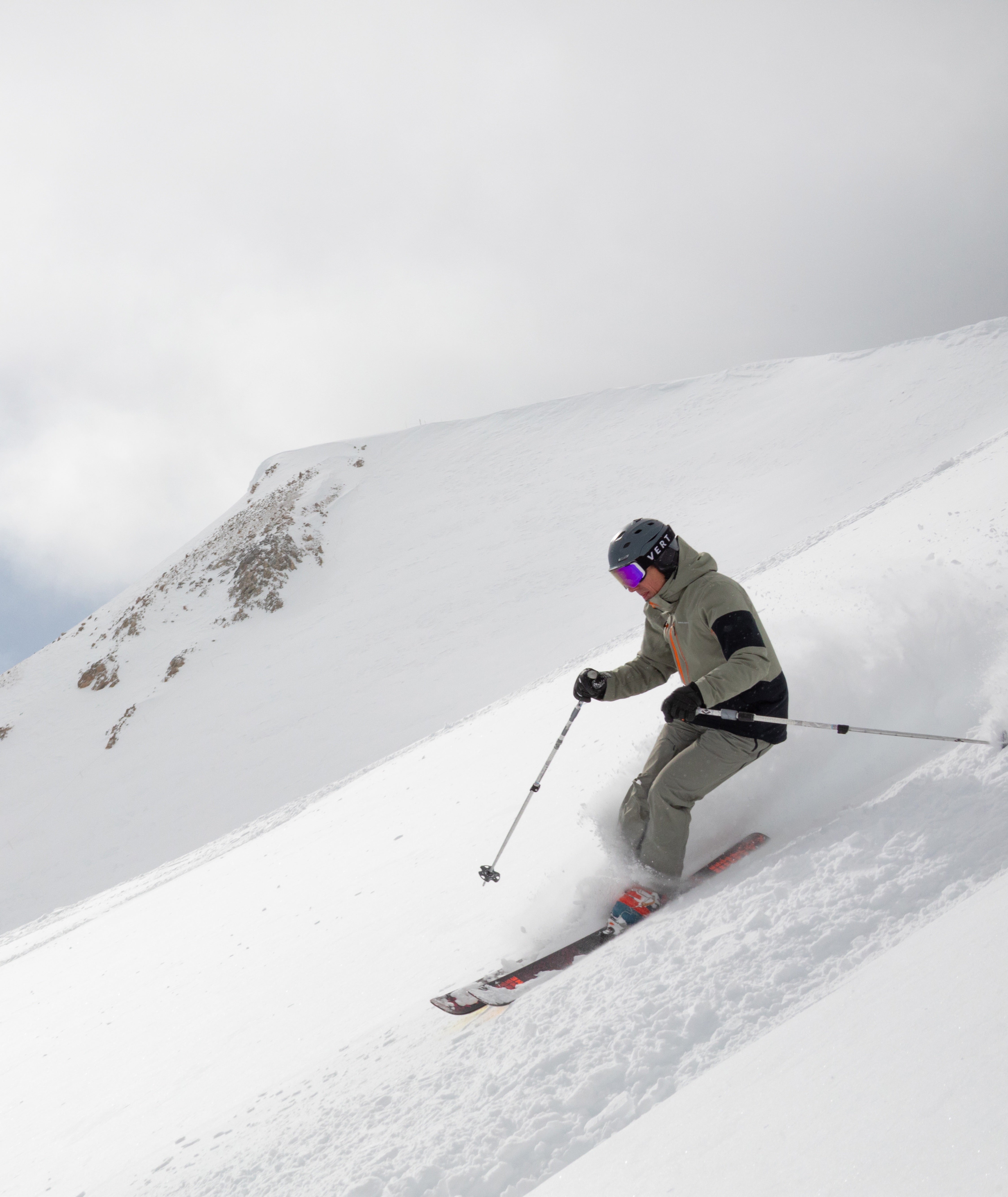Person skiing down a snowy slope with a mountain in the background