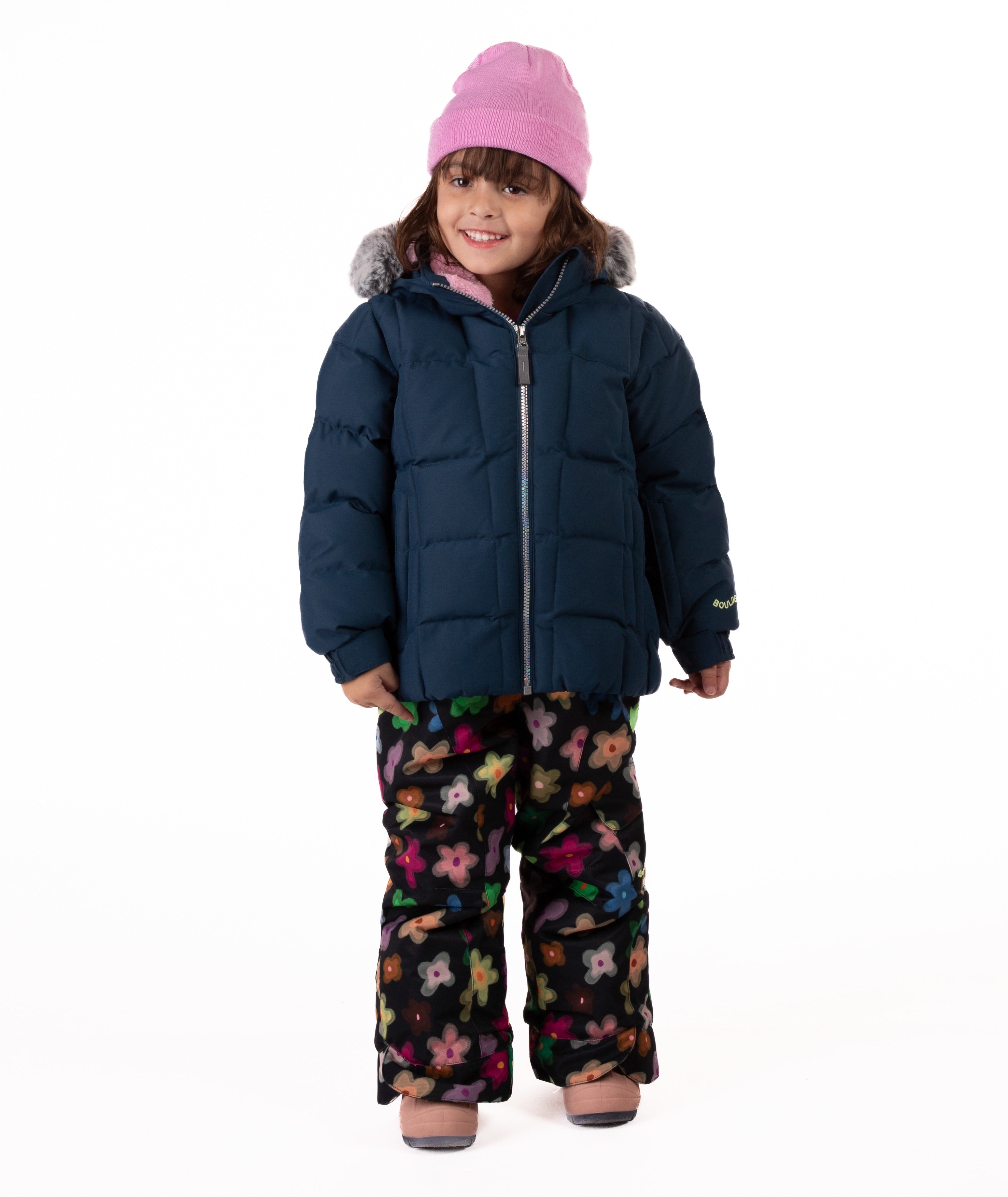 Child wearing a navy blue quilted puffy winter coat on a white background