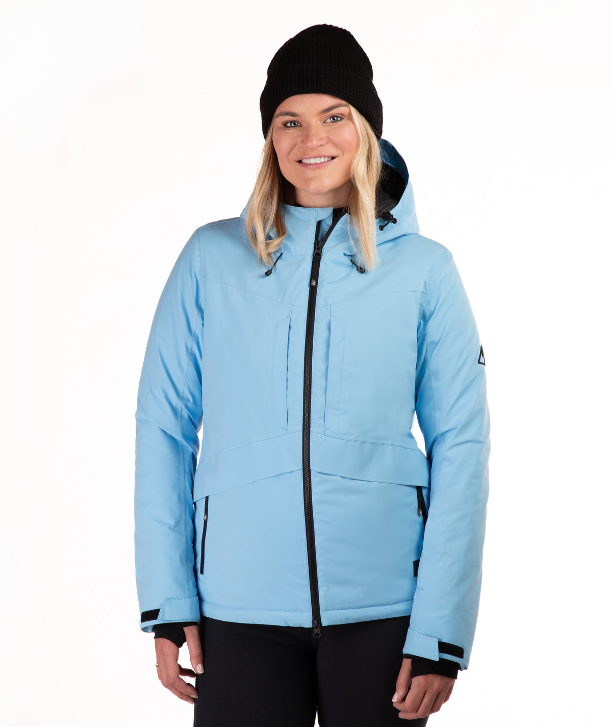 A woman wearing a light blue ski jacket with black trim, a black beanie, and black pants, photographed against a plain white studio background.